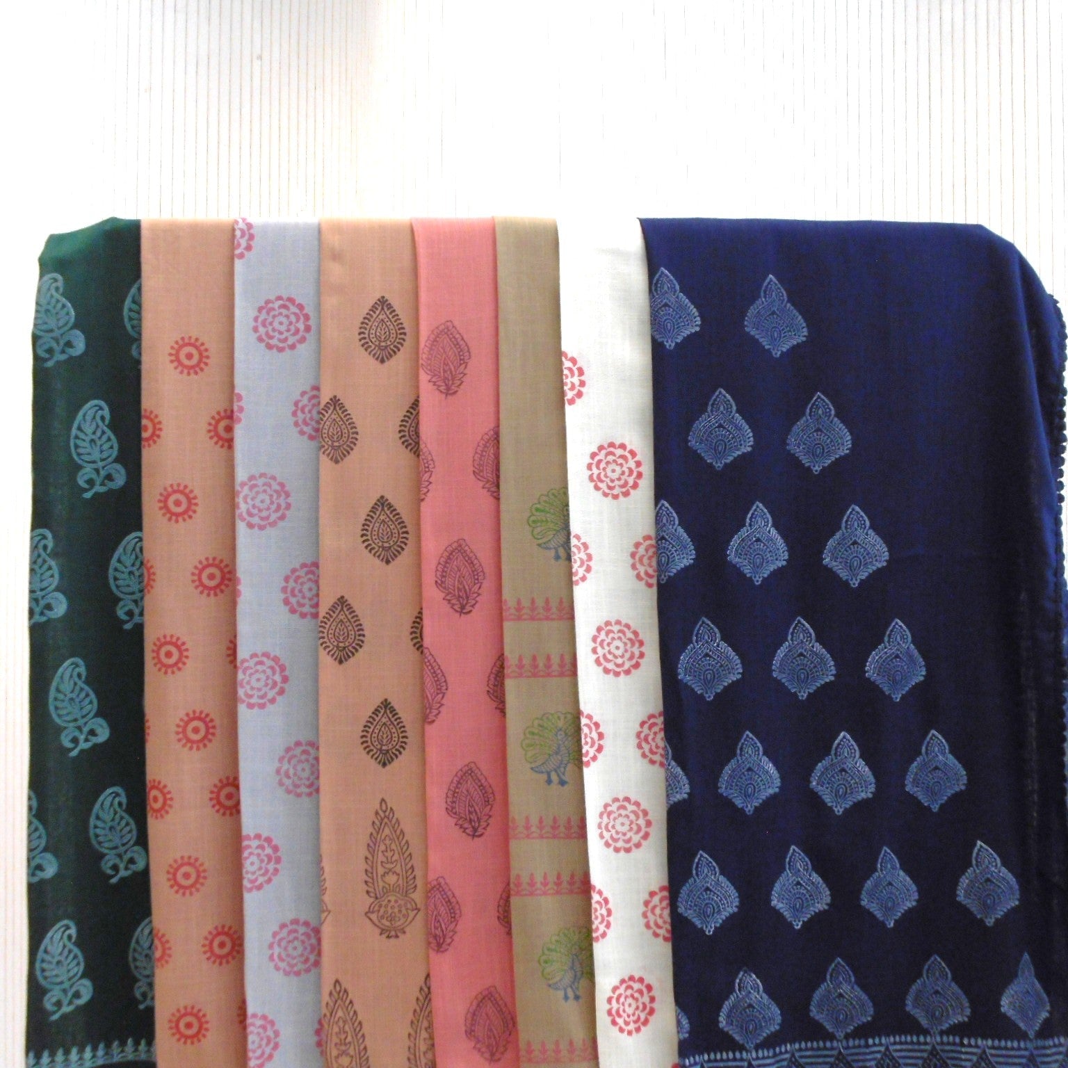 Hand block printed cotton viscose scarves in multiple colours including navy, teal, pink, peach and white, laid flat showing ethnic floral and paisley block print designs
