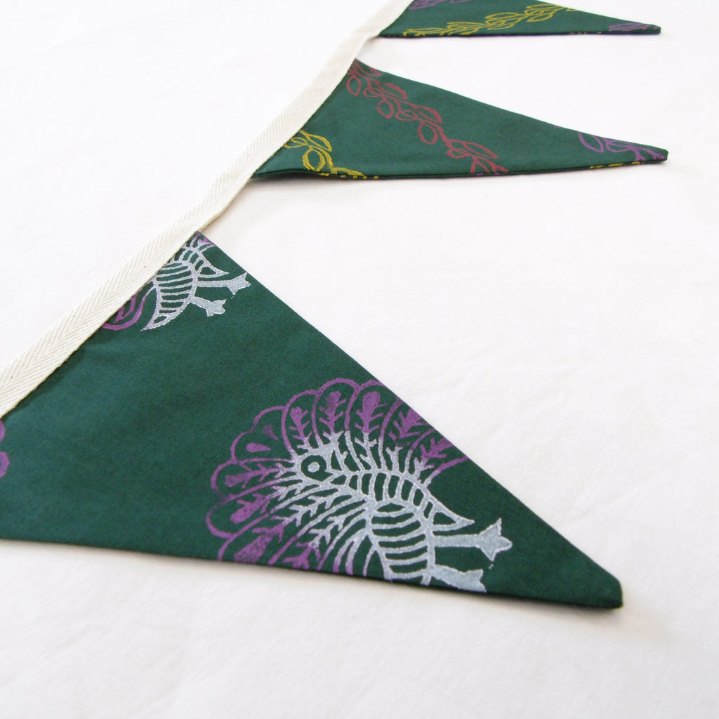 Close up of hand block printed peacock motif on green cotton bunting flag