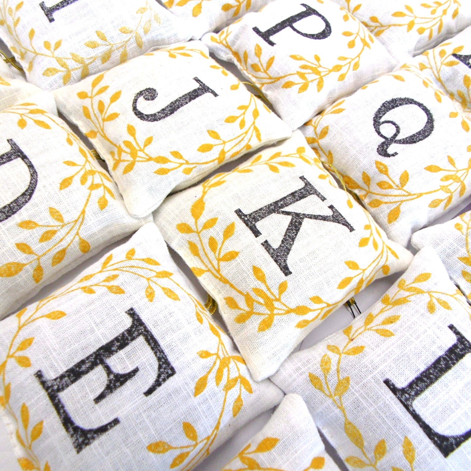 Hand block printed alphabet lavender sachets showing letters J K E P Q and more with golden leaf design, by Naila Ahmad London