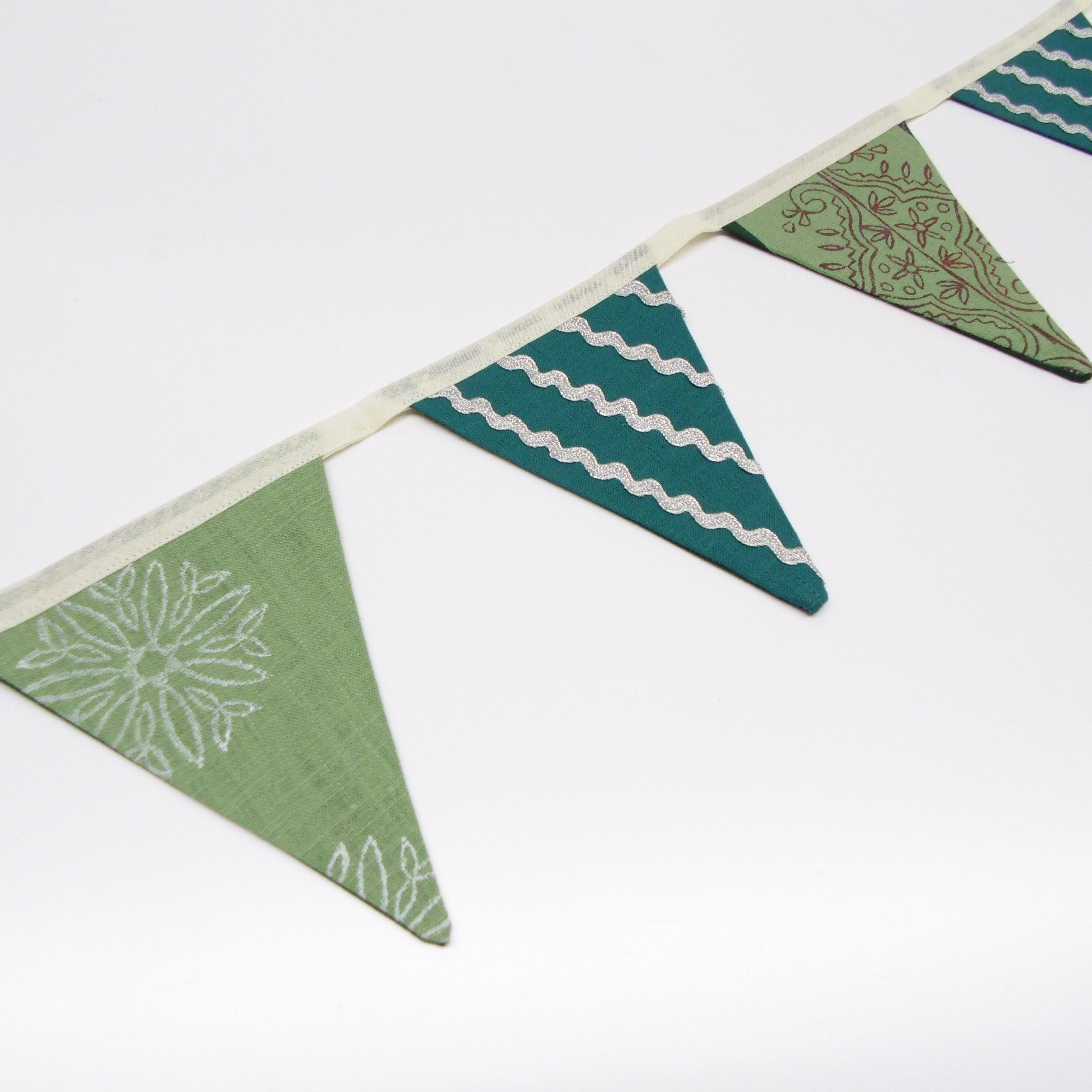 Detail of hand block printed teal and sage green bunting flags with paisley and wave designs