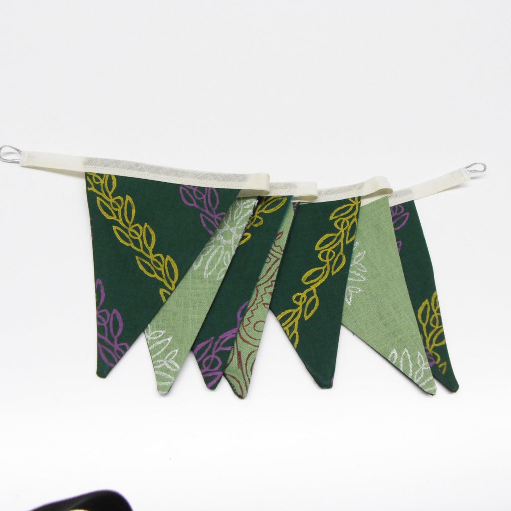 Full length view of green hand block printed cotton linen flag garland hanging with vine and floral motifs