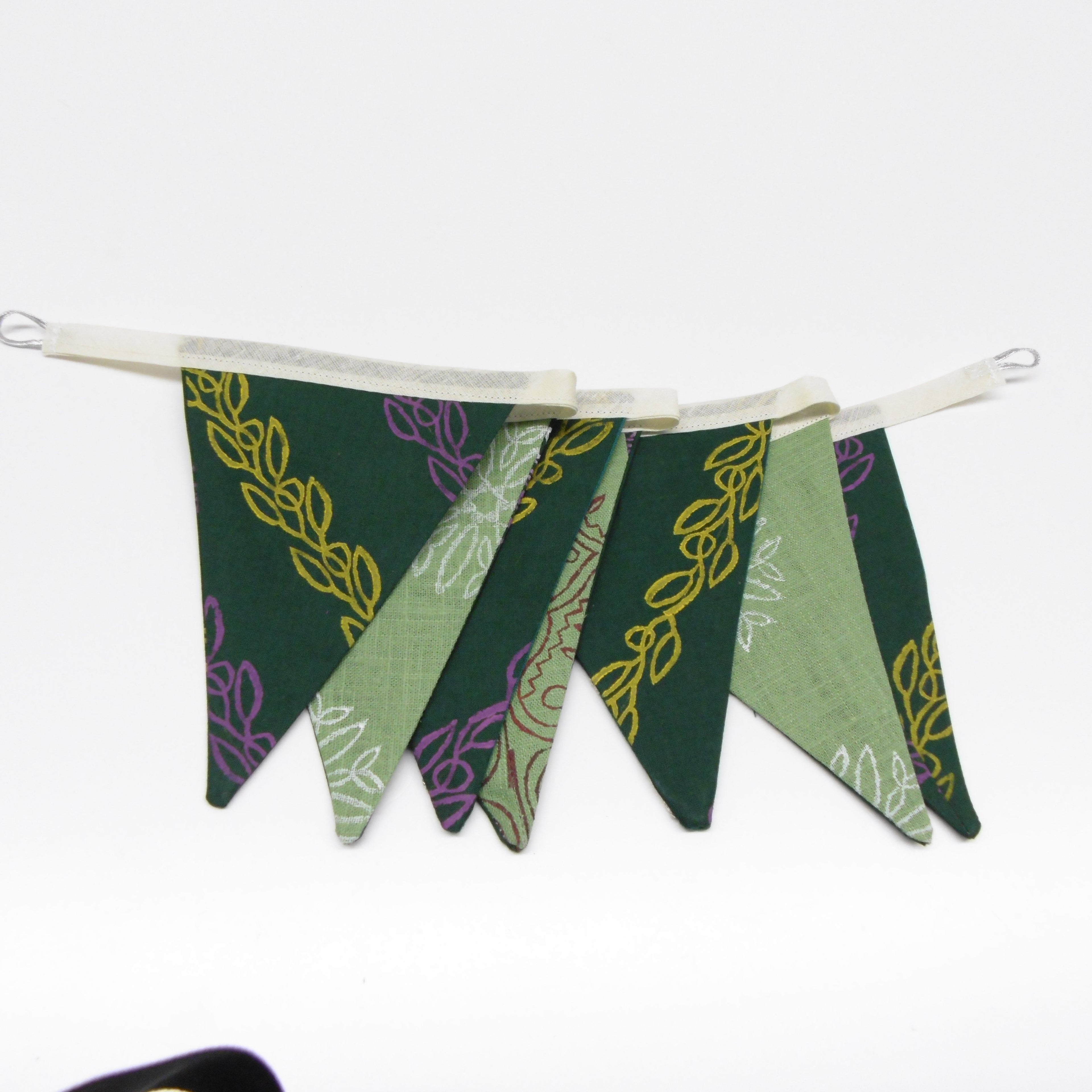 Full length view of green hand block printed cotton linen flag garland hanging with vine and floral motifs