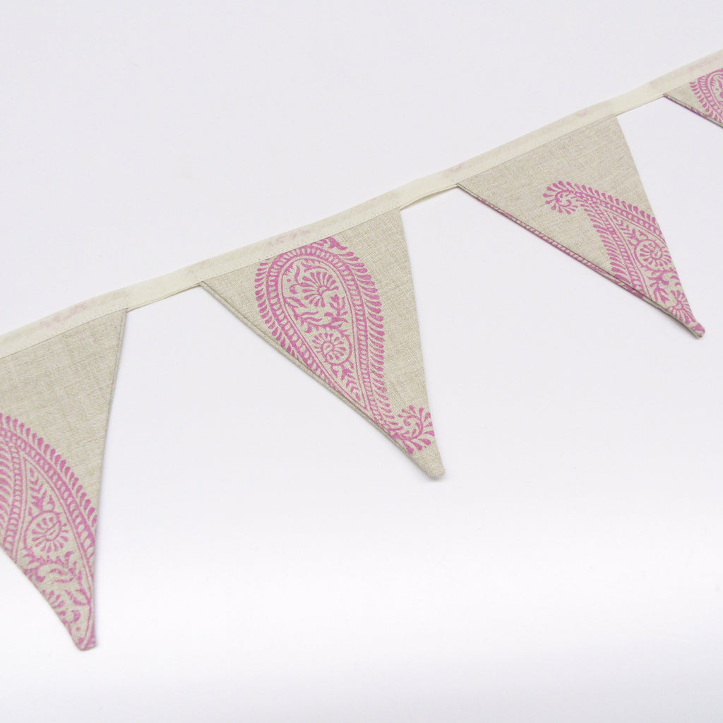 Close up of large pink paisley hand block print on natural oatmeal linen bunting flags
