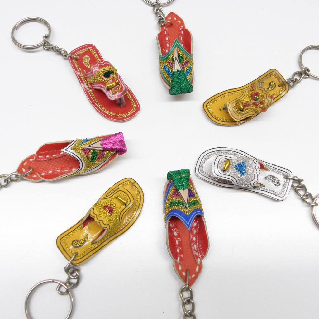 Miniature leather Pakistani chappal and khussay keyrings spread out showing gold and red designs with metallic thread