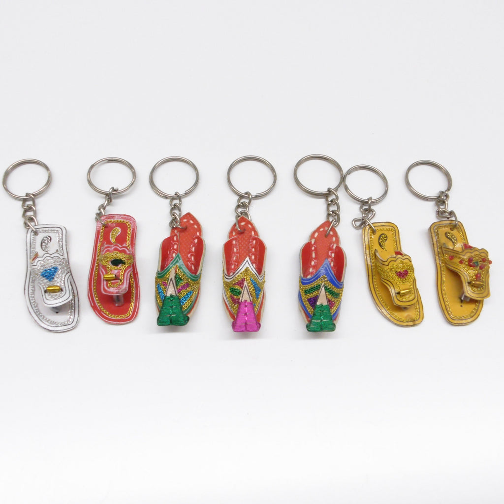 Seven miniature leather Pakistani chappal and khussay keyrings in a row showing assorted colours including red, gold and silver