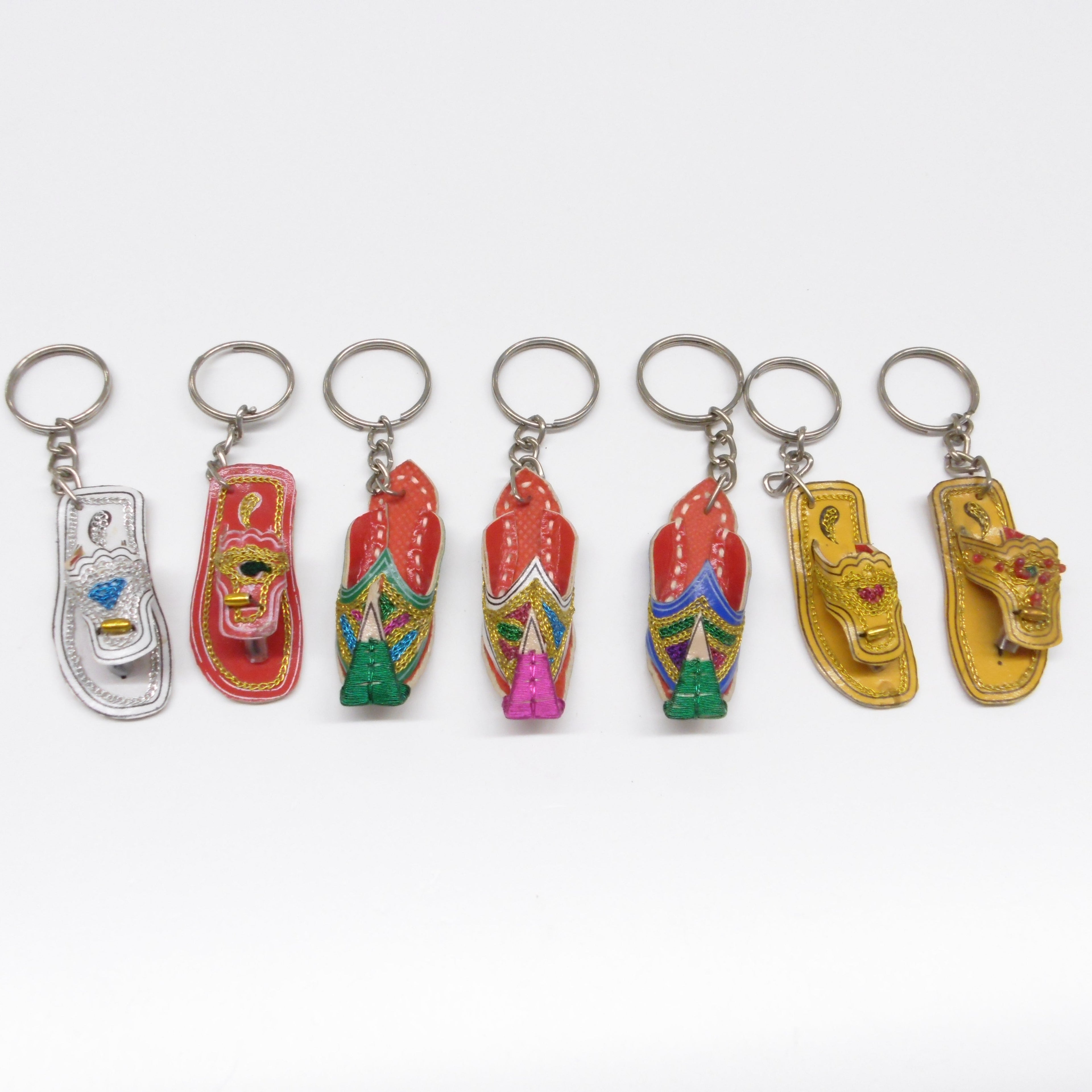 Seven miniature leather Pakistani chappal and khussay keyrings in a row showing assorted colours including red, gold and silver