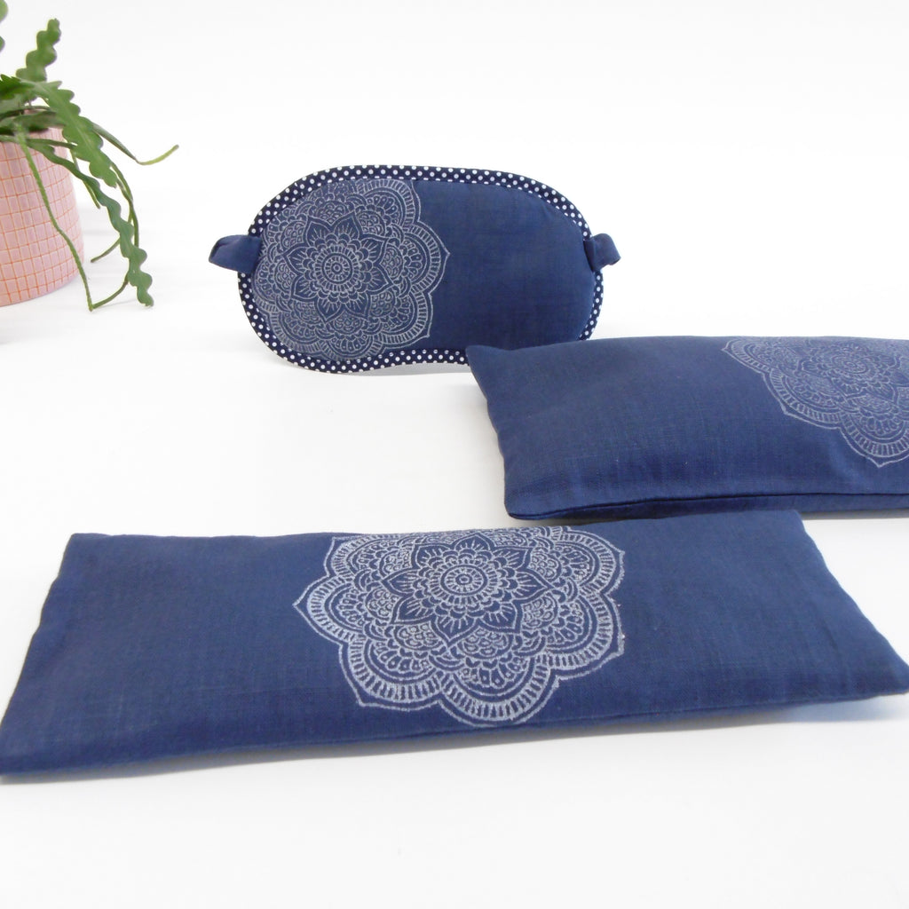 Set of blue eye pillow and cushion with white mandala design on a white background