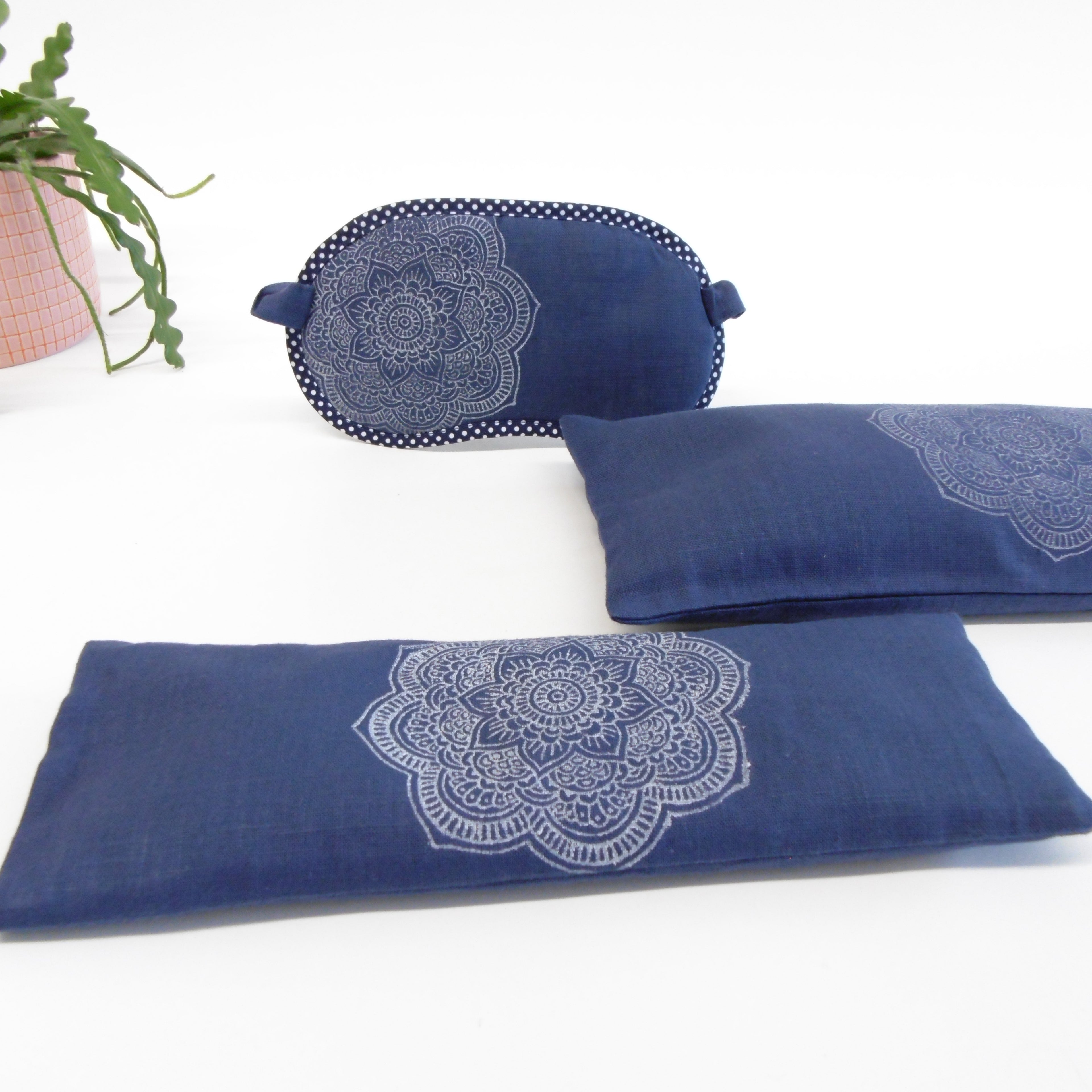Set of blue eye pillow and cushion with white mandala design on a white background