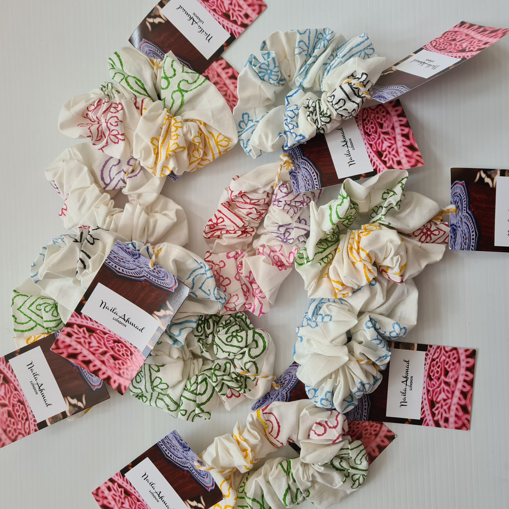 Colorful scrunchies with branded labels on a white surface
