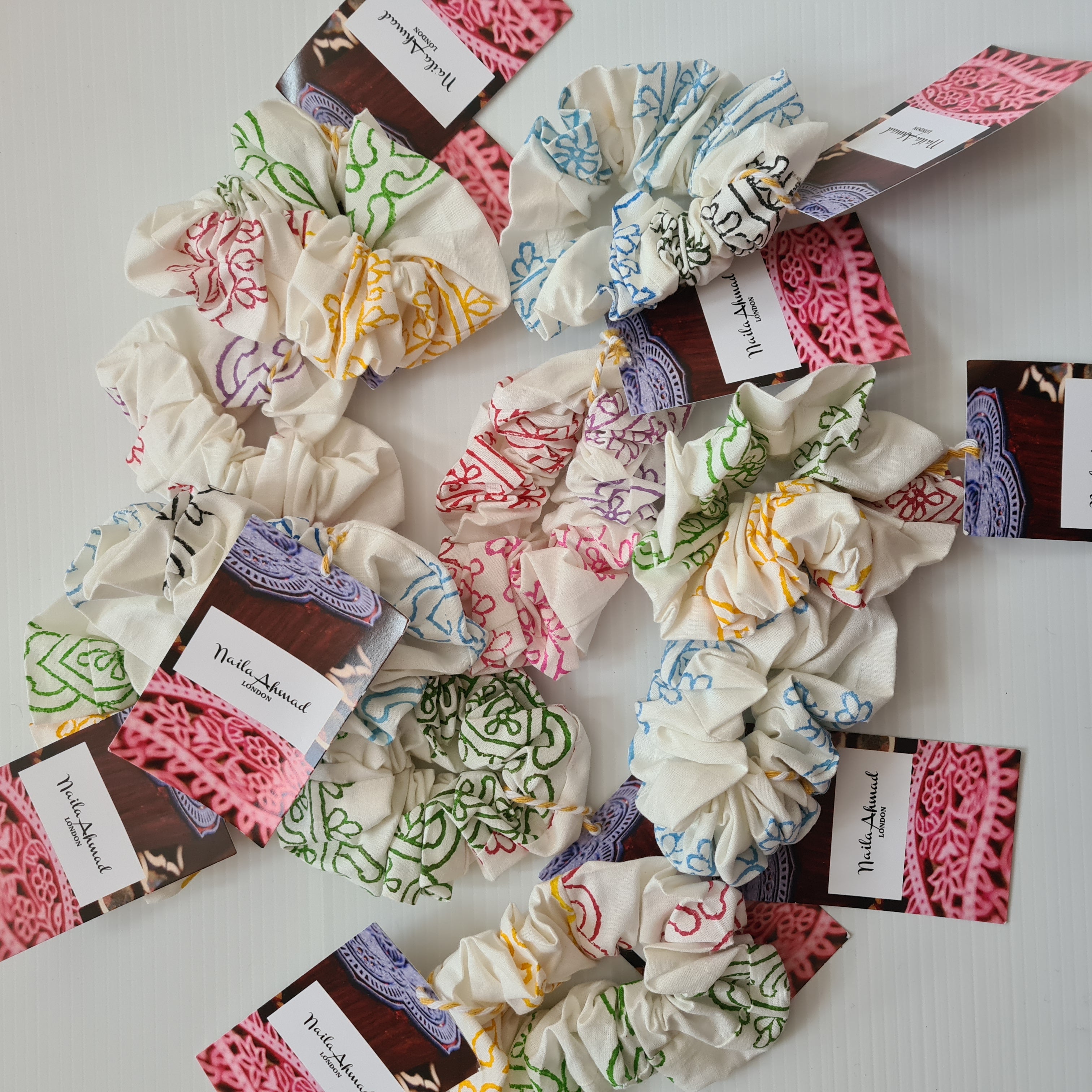 Colorful scrunchies with branded labels on a white surface