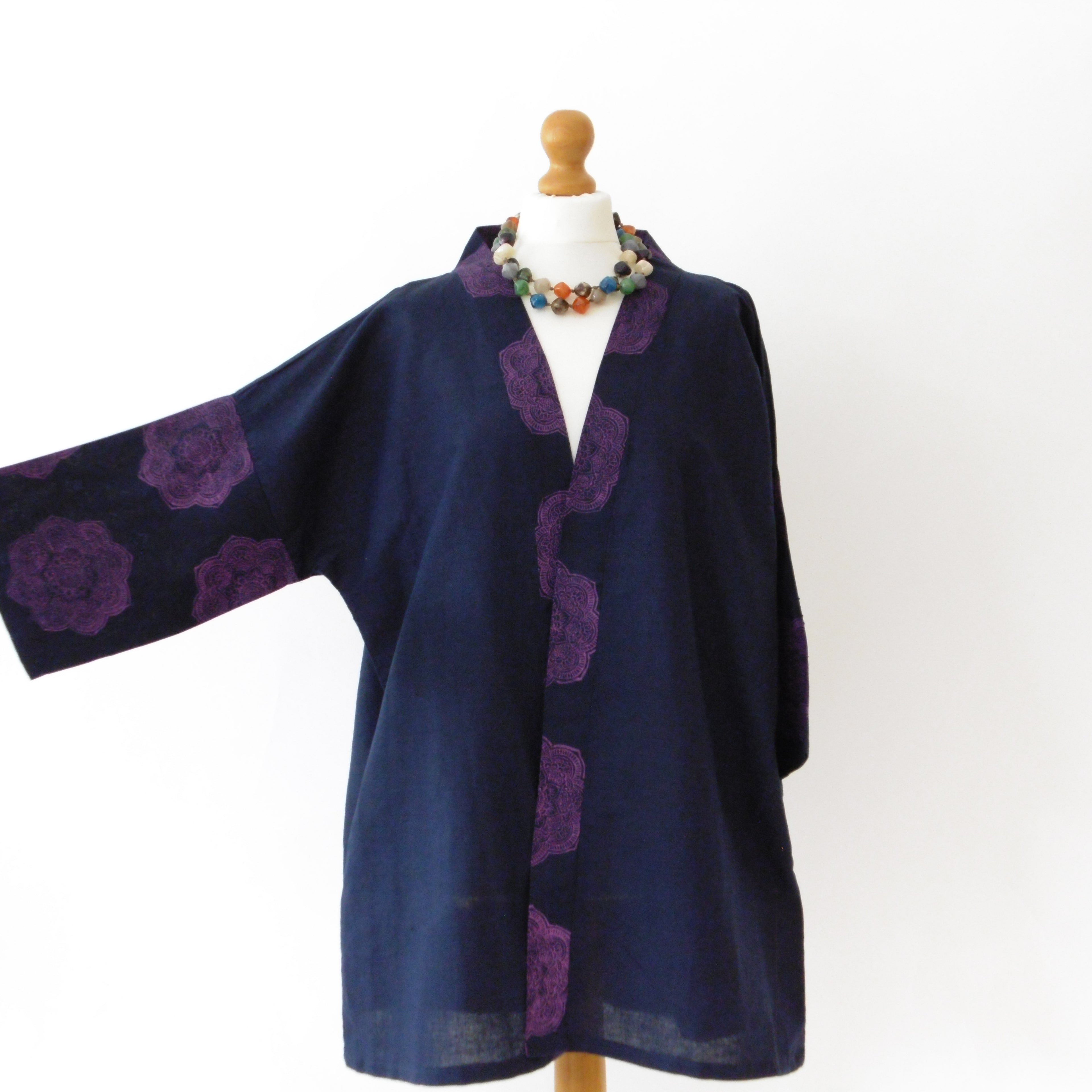 Navy blue cardigan with purple floral patterns on a mannequin against a white background