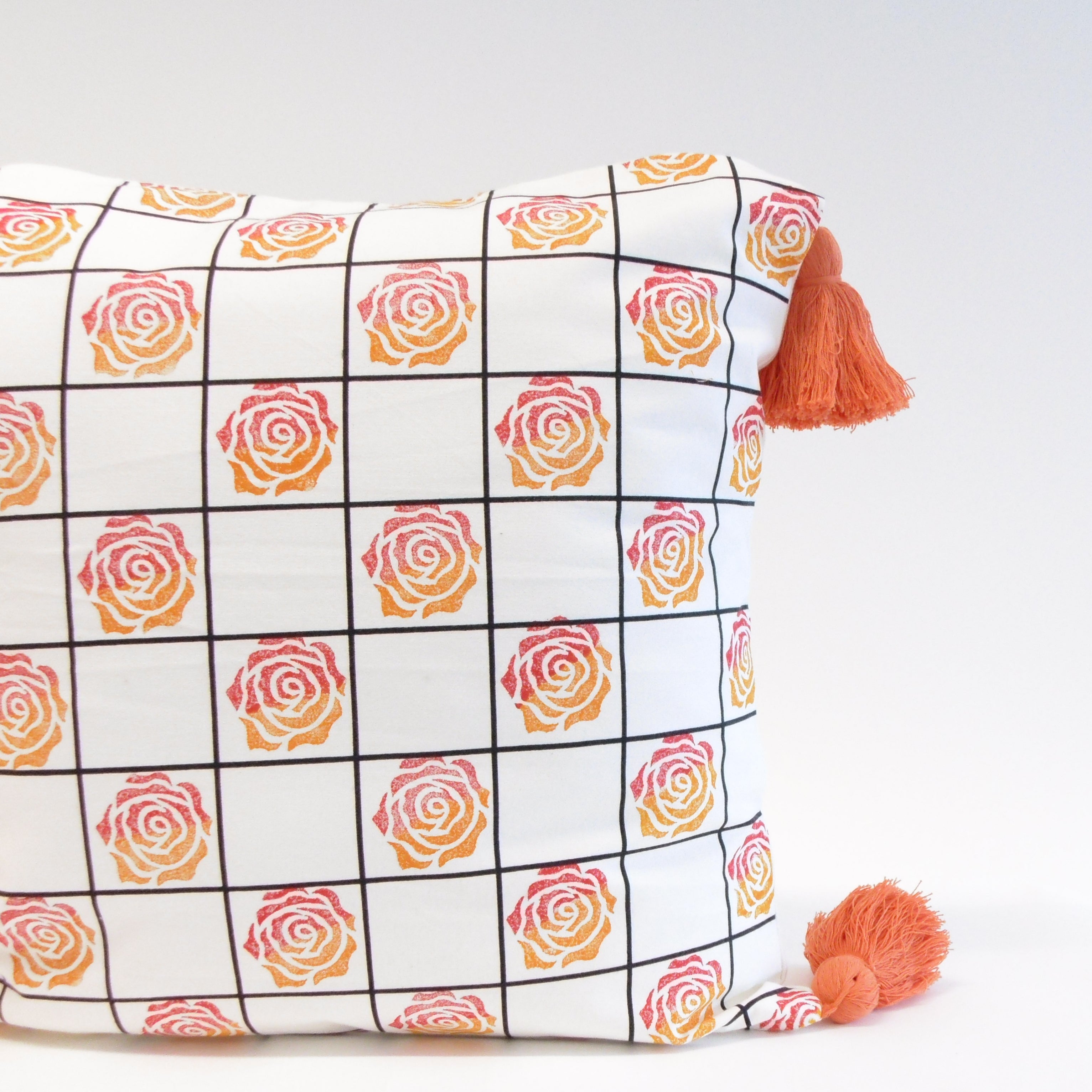 Decorative pillow with rose pattern and tassels on a white background