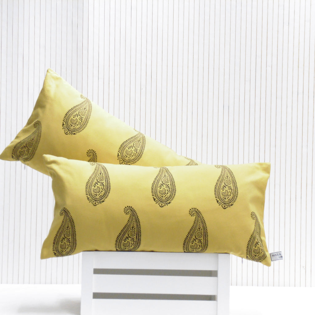 Two yellow pillows with black patterns on a white chair against a white background