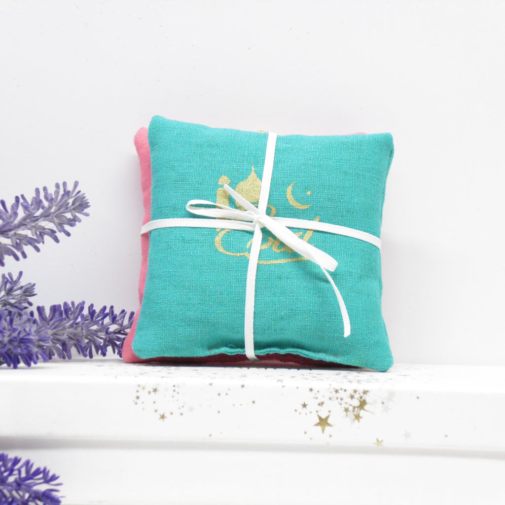 Turquoise fabric pouch with white ribbon on a white background with lavender flowers.