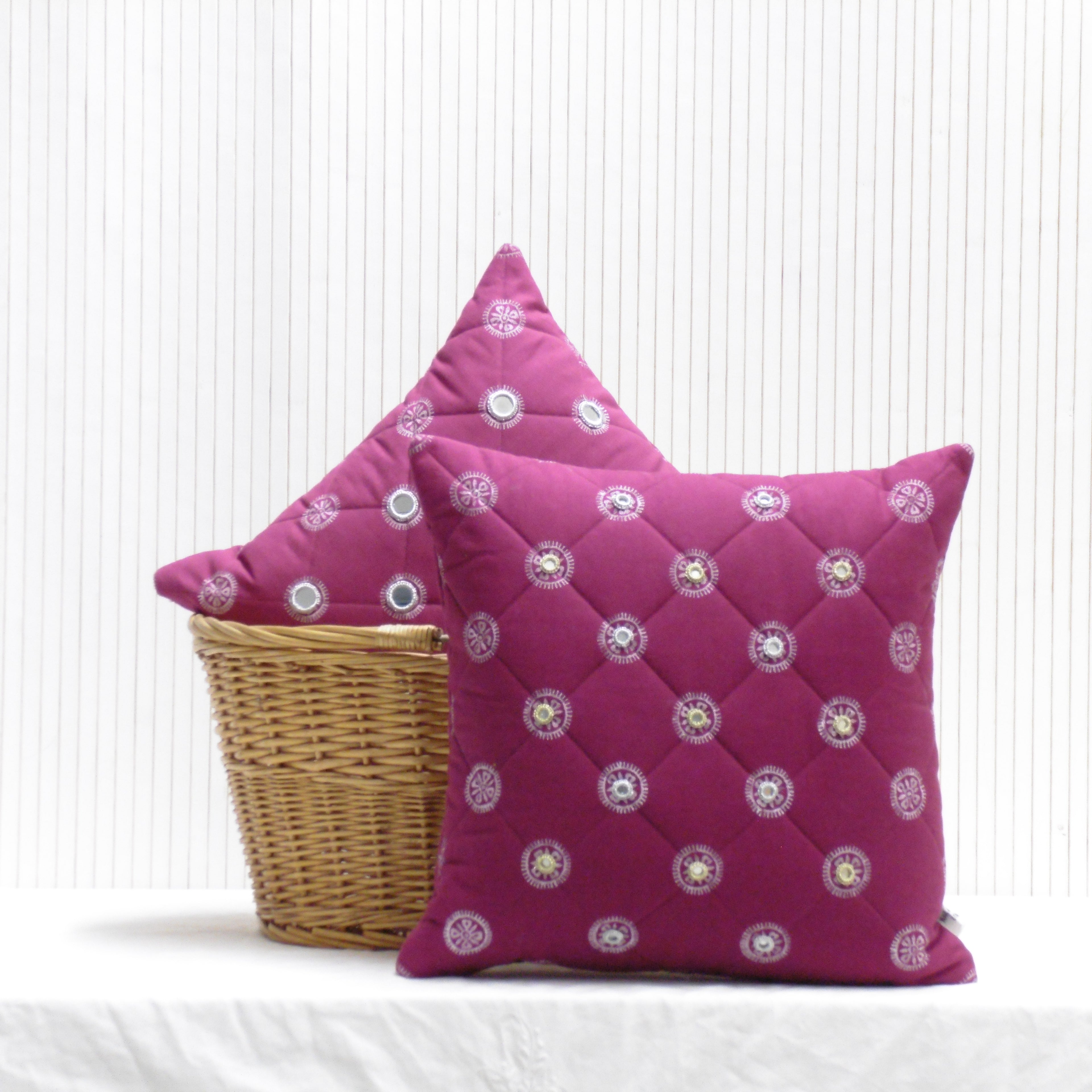 Two pink decorative pillows with a basket on a white background