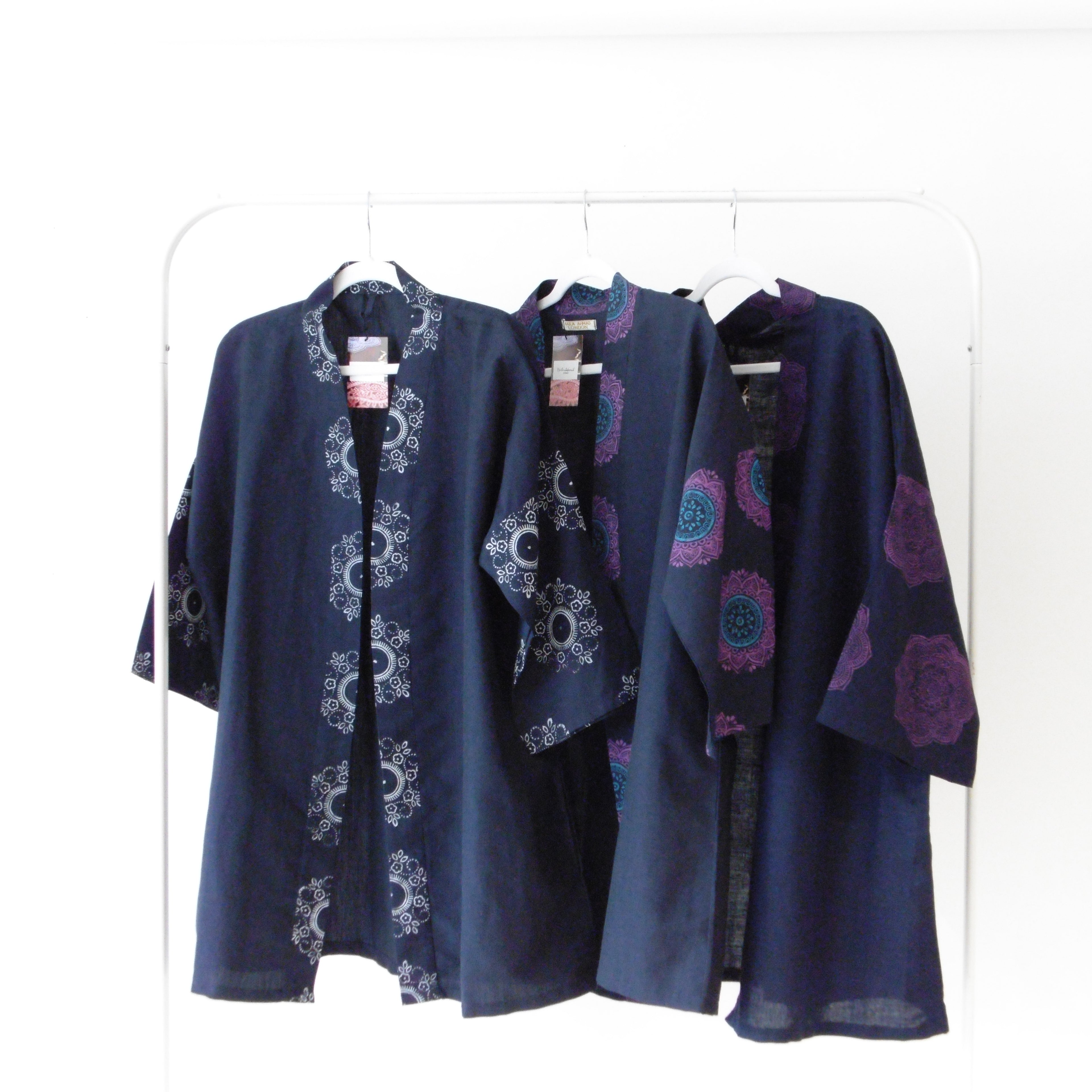 Navy blue jackets with intricate patterns on a white rack
