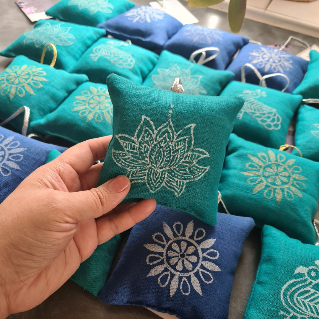 Teal fabric pouches with white floral patterns held by a hand, surrounded by more pouches.