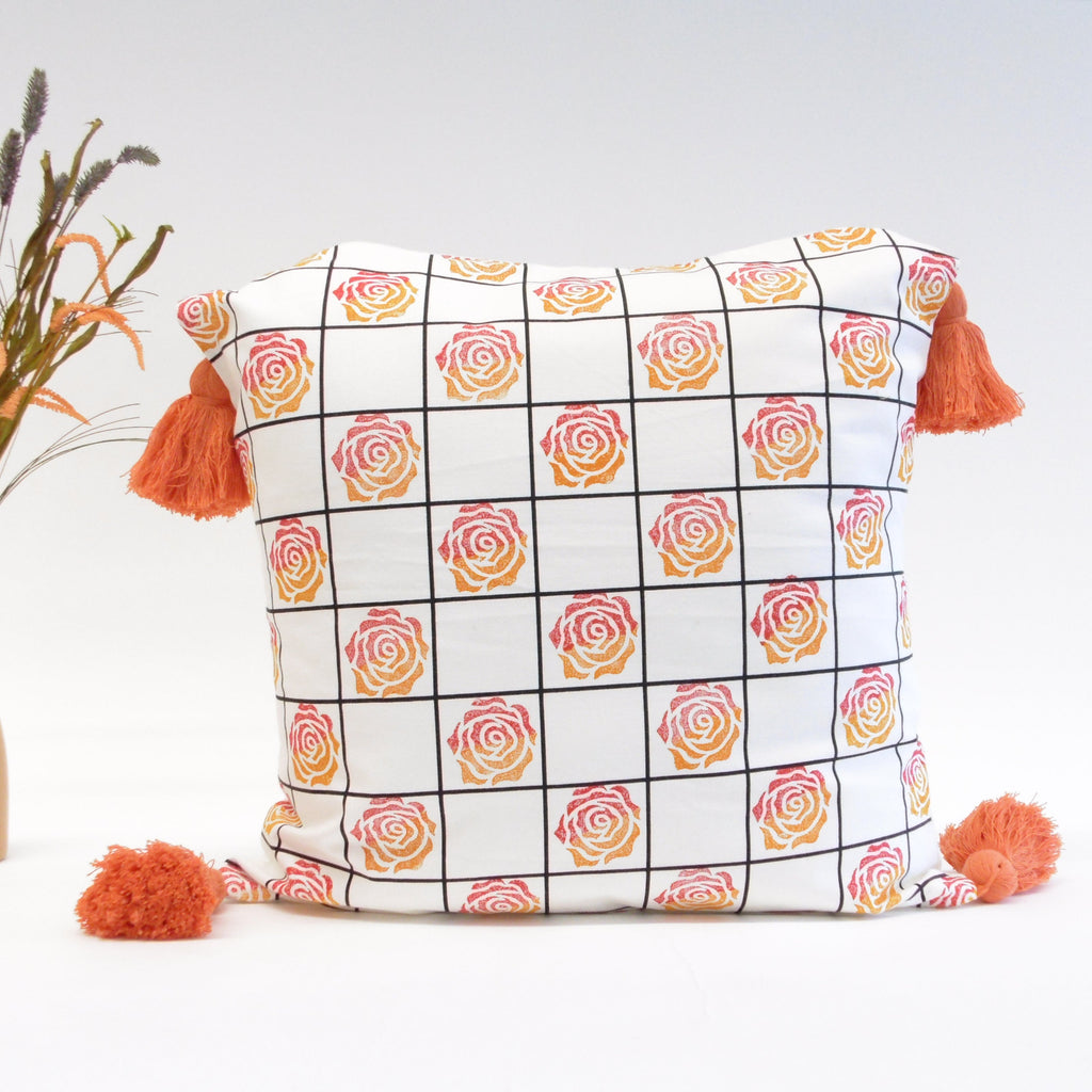 Decorative pillow with rose pattern and tassels on a light background