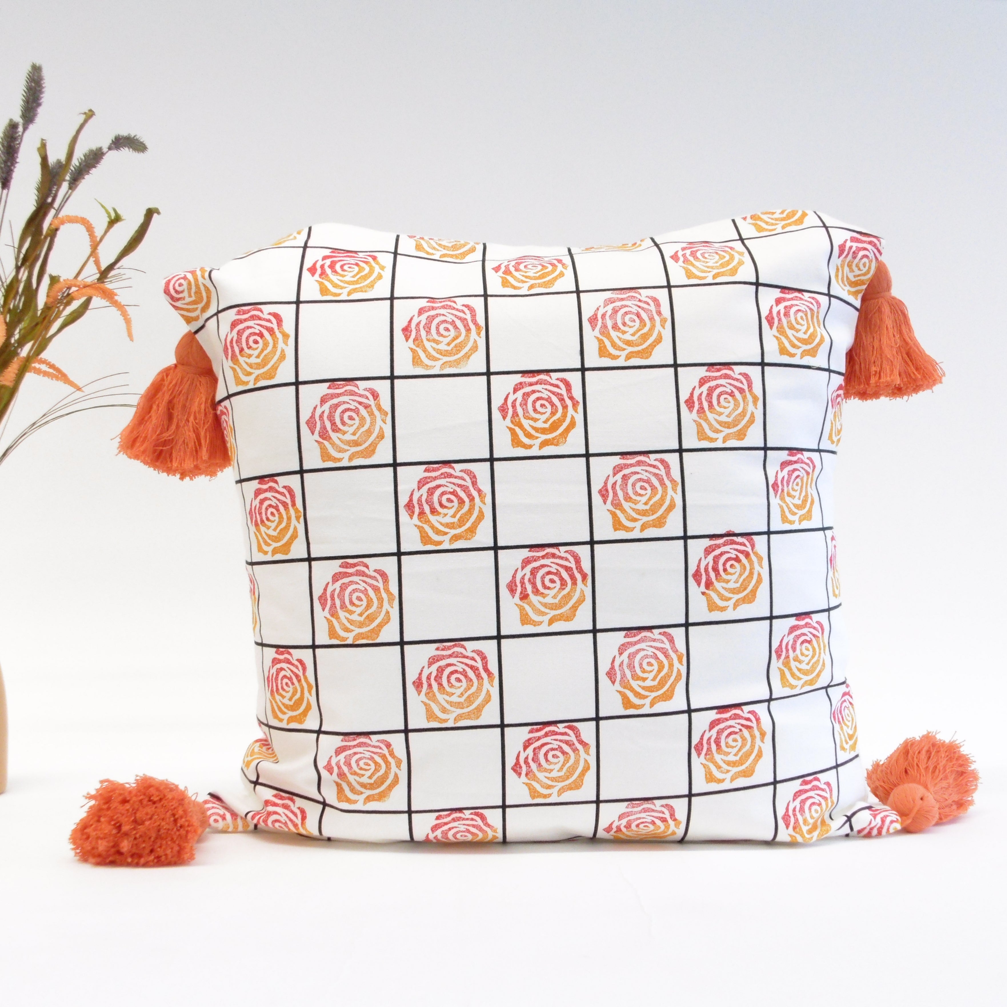 Decorative pillow with rose pattern and tassels on a light background