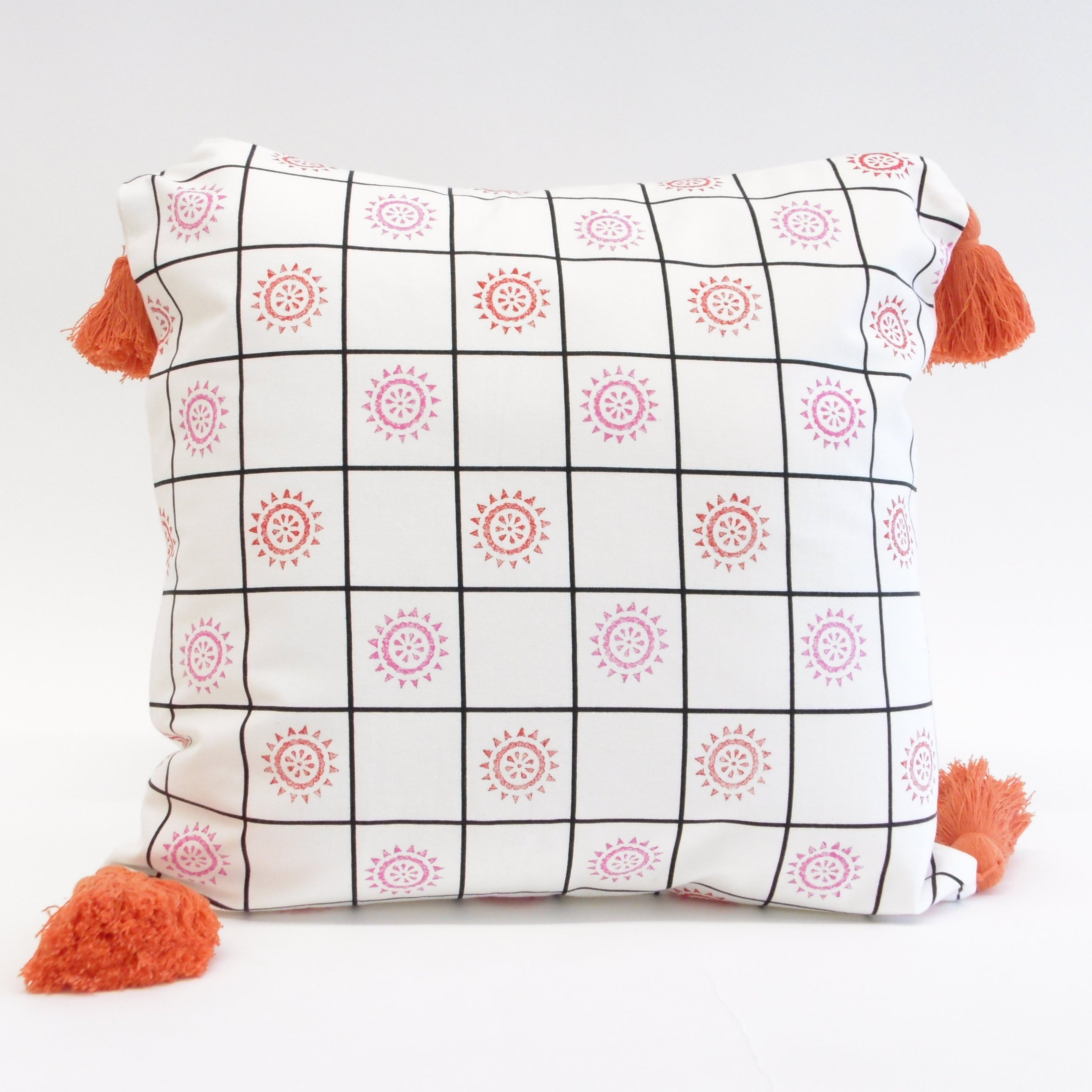 Decorative pillow with geometric pattern and orange tassels on a white background