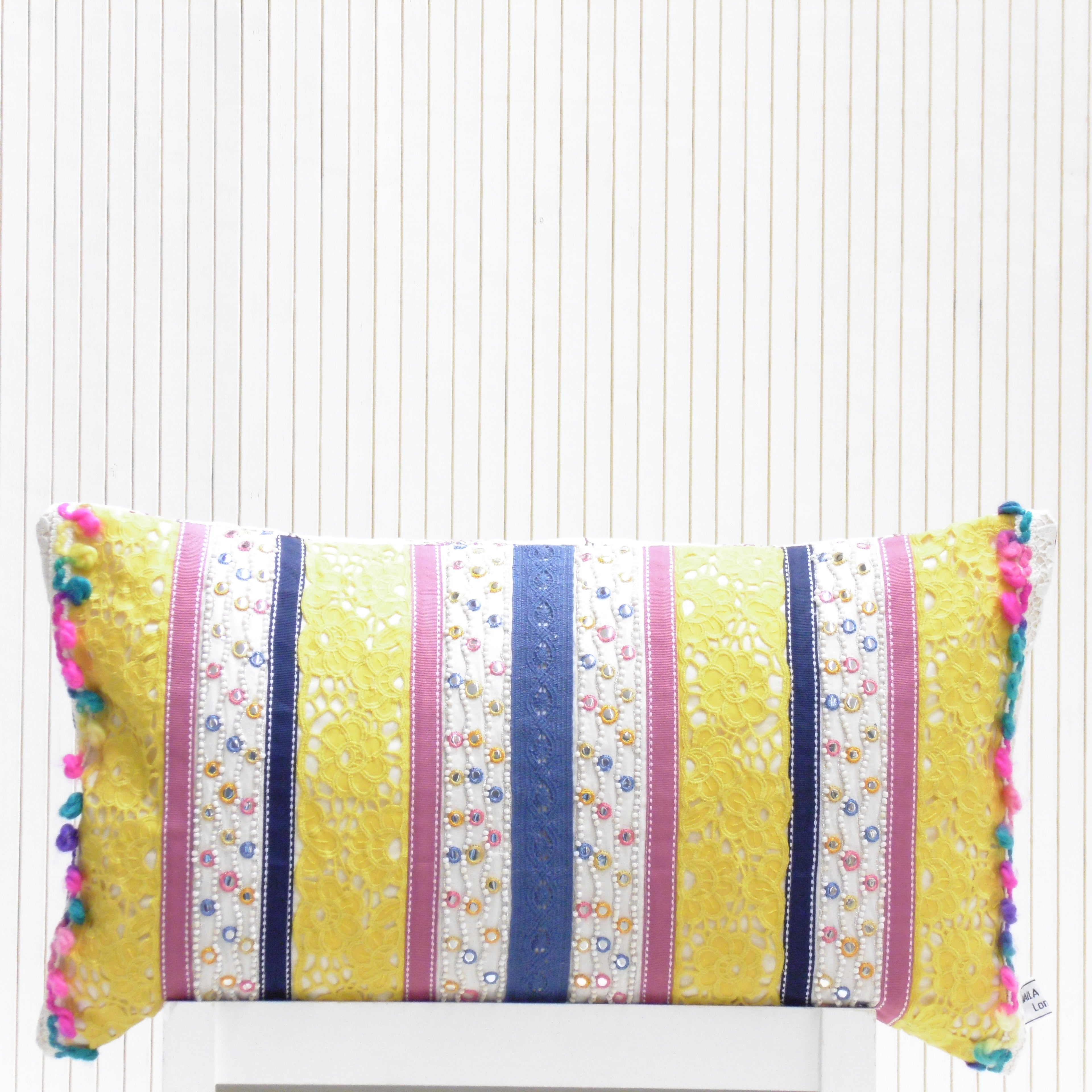 Decorative pillow with colorful stripes and pom-poms on a white background