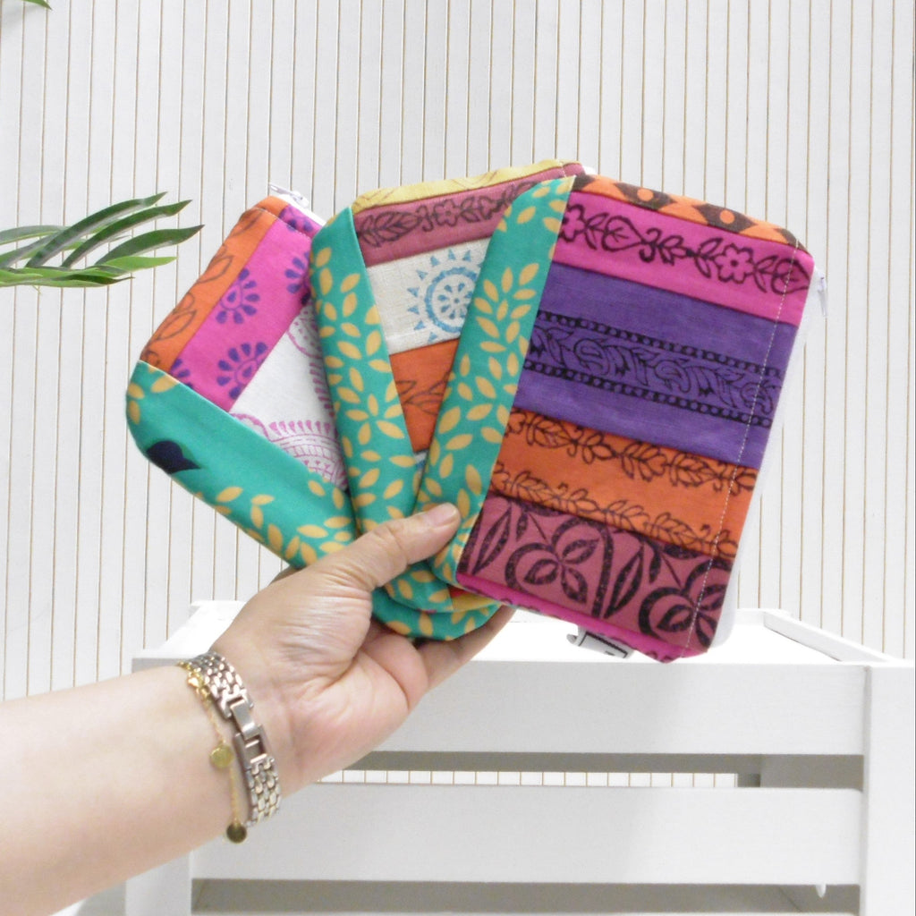 Hand holding a colorful patterned pouch against a white background