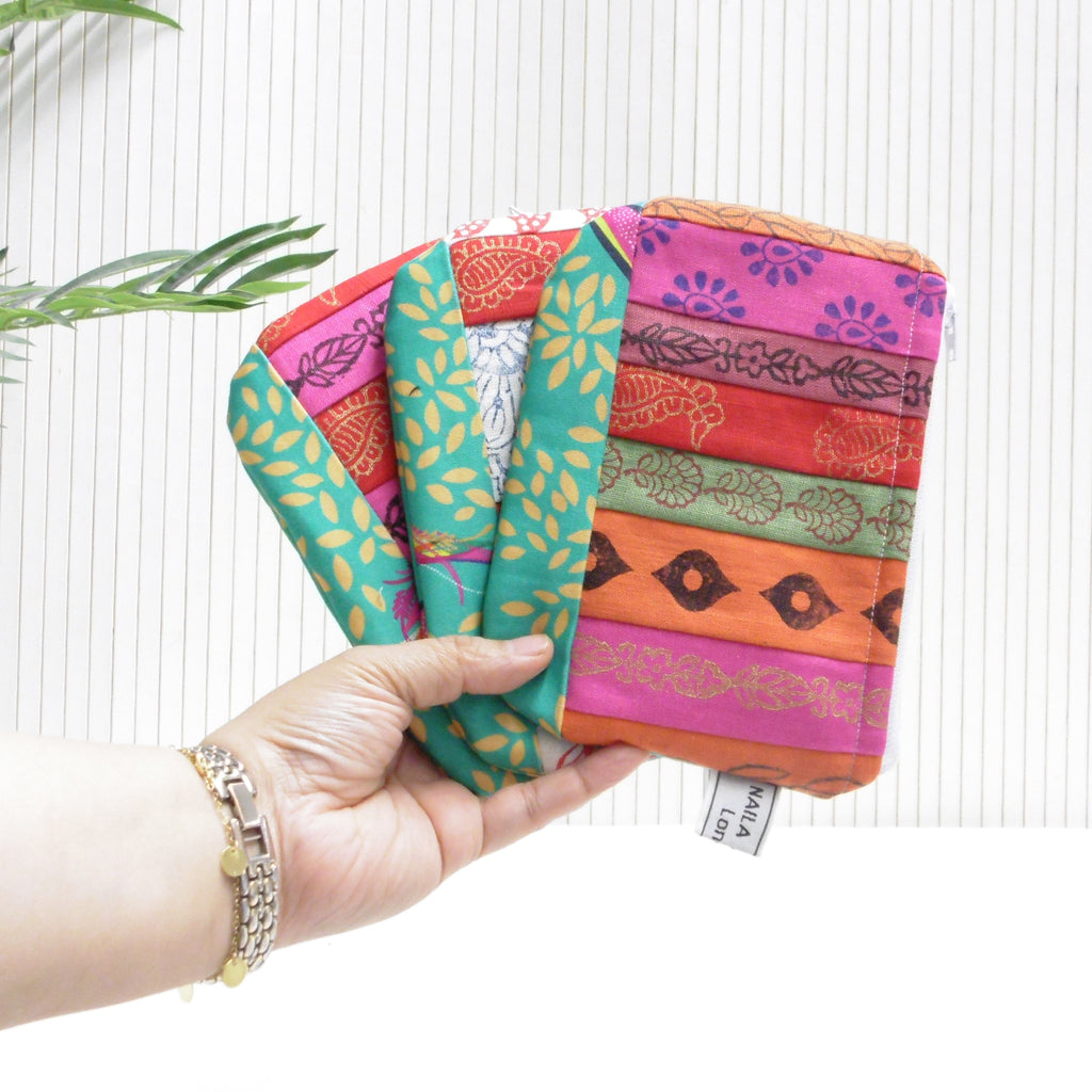 Hand holding a colorful fabric pouch with patterns on a white background