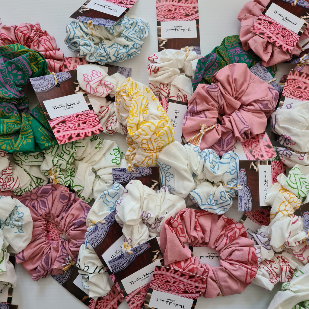 Collection of colorful scrunchies on a white surface with visible brand labels.