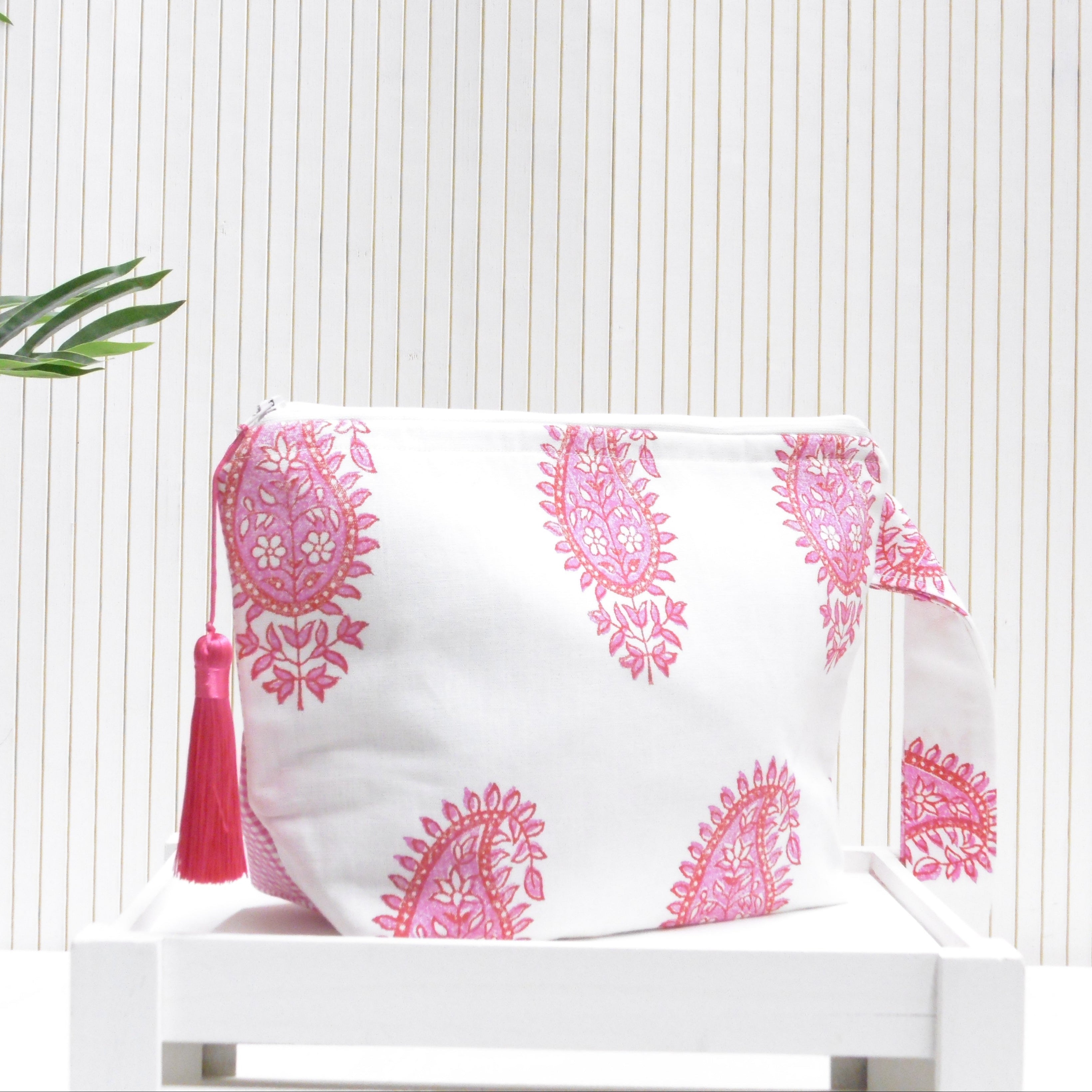 White pouch with pink floral patterns and a tassel on a white background