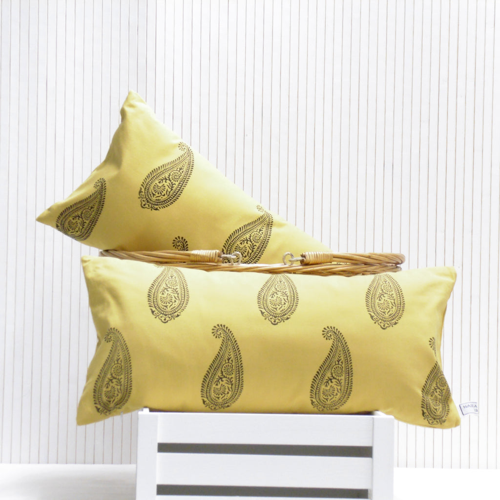 Two yellow pillows with gold patterns on a white background