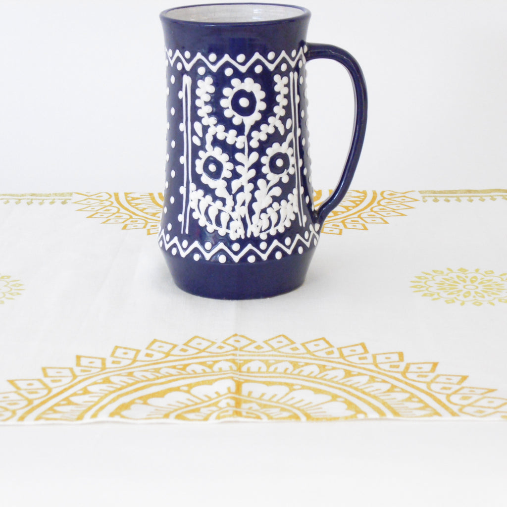 Navy blue mug with white floral pattern on a white background with gold decorative elements.