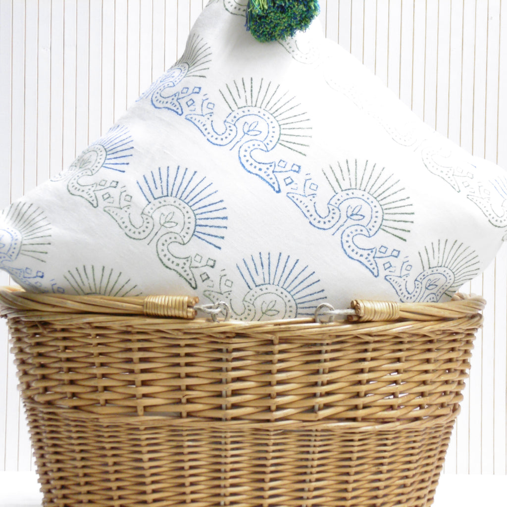 Wicker laundry basket with a white pillow featuring blue patterns on a white background