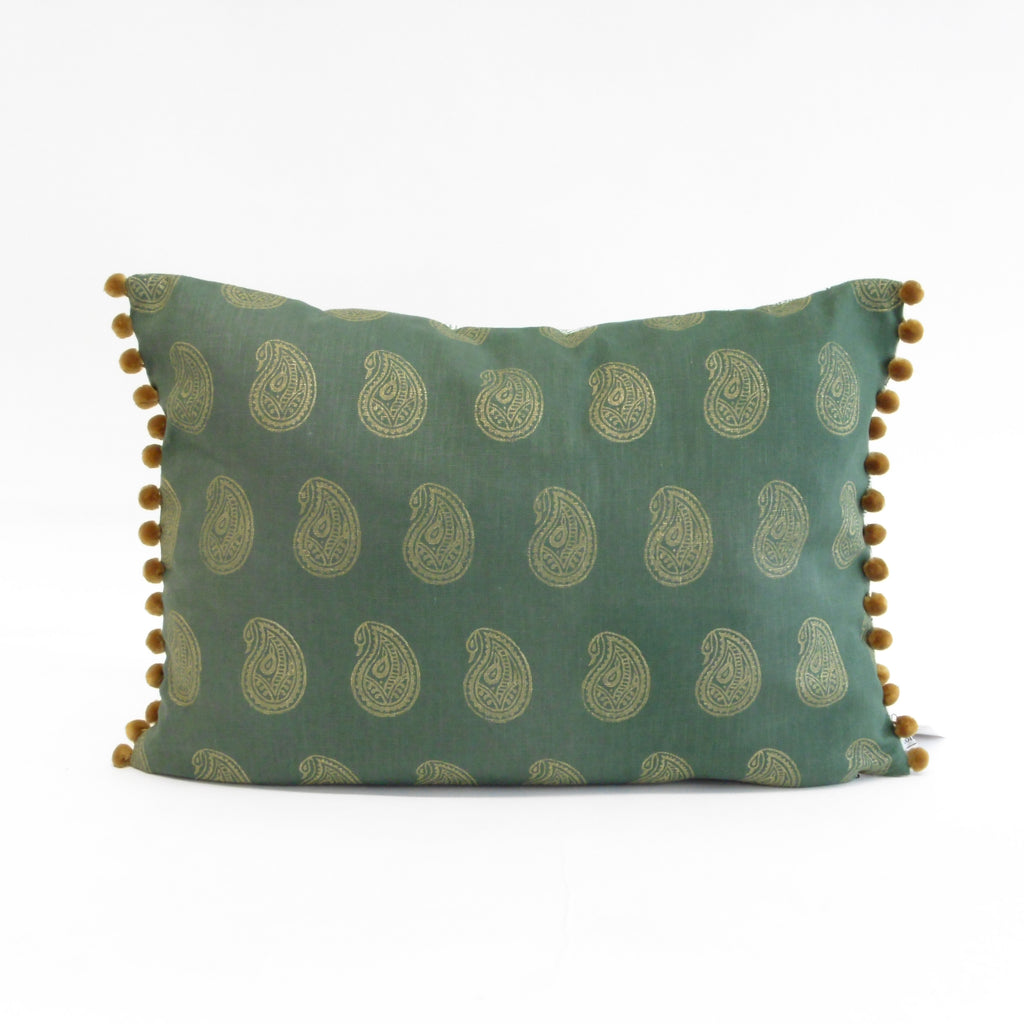 Green pillow with paisley pattern and pom-pom trim on a white background