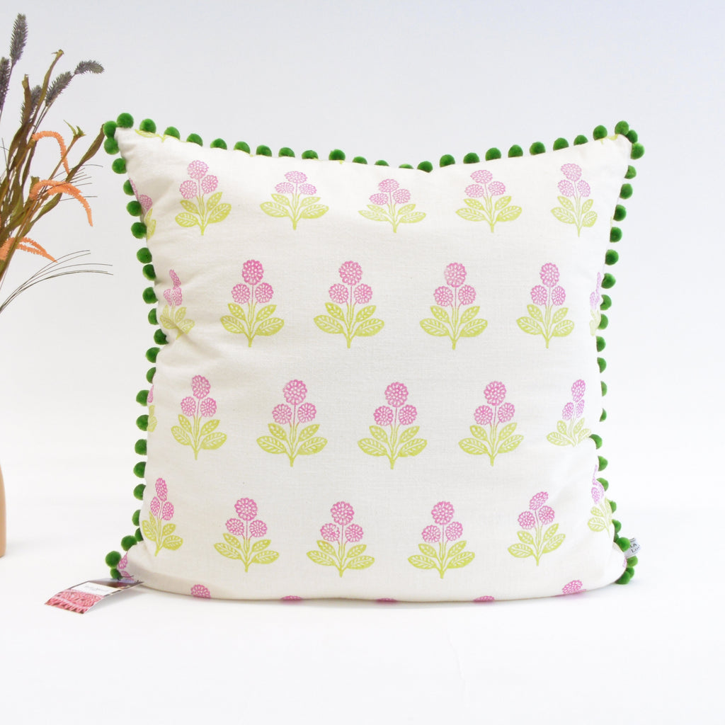 Decorative pillow with floral pattern and green pom-pom trim on a white background
