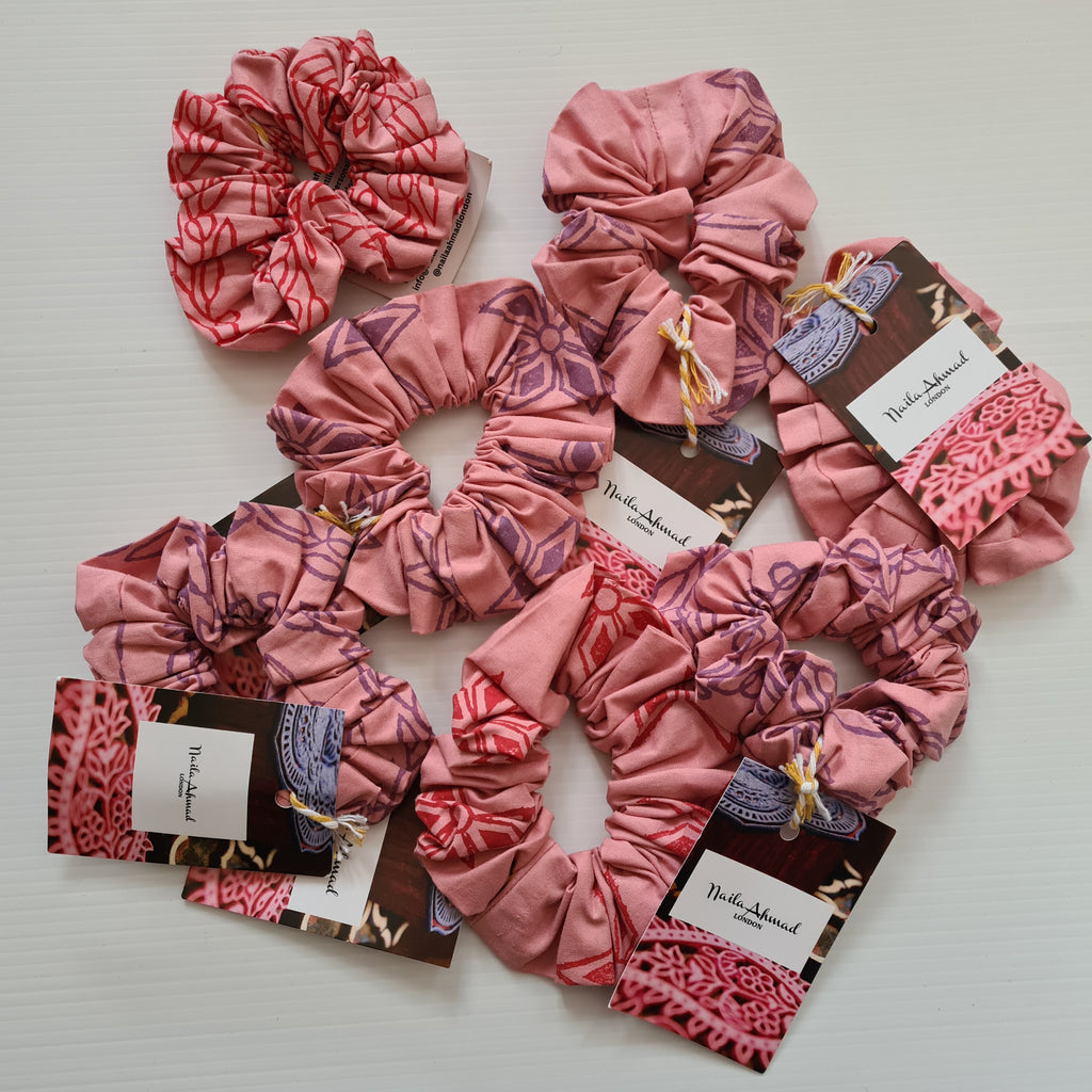 Pink scrunchies with branded cards on a light background