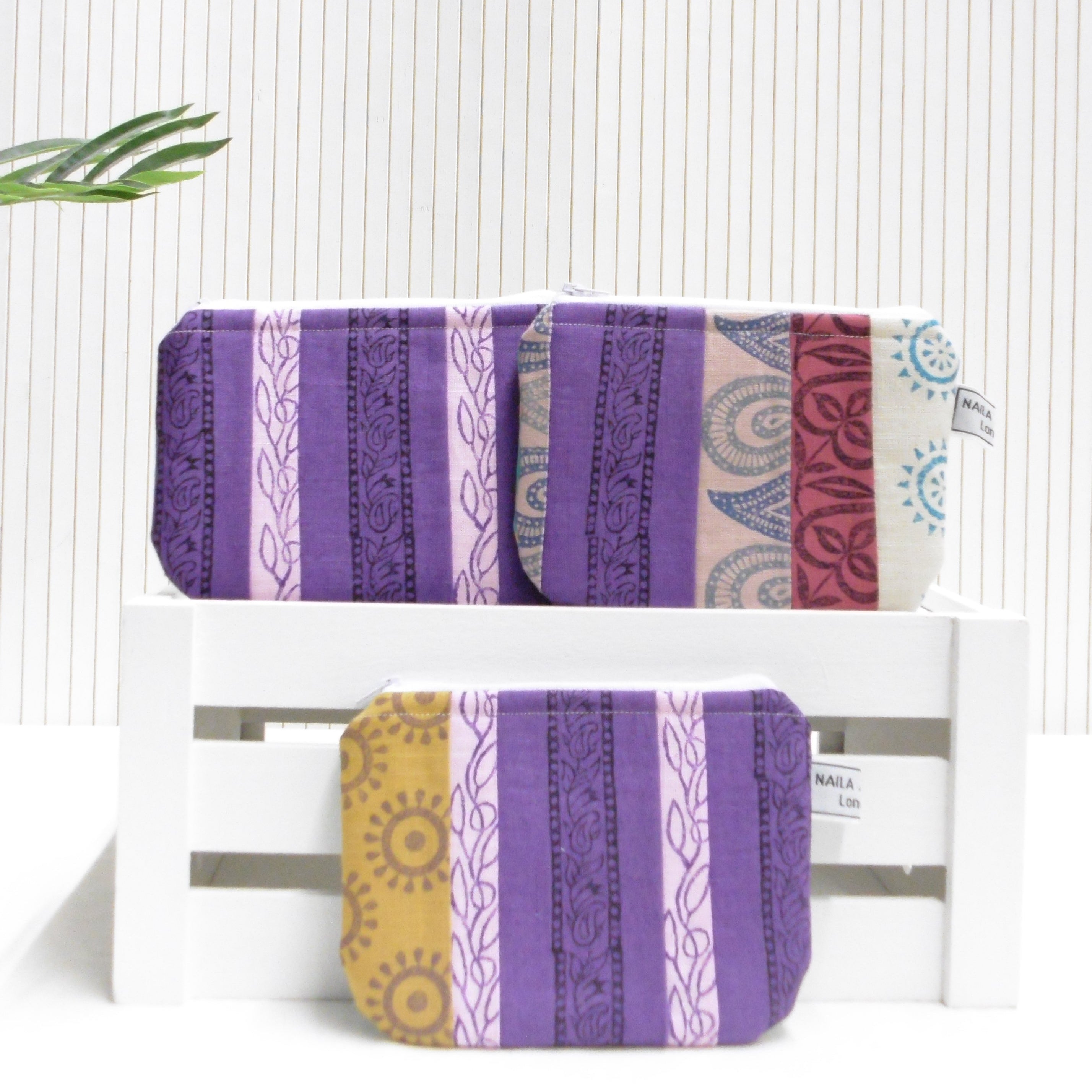 Two purple and yellow patterned pouches on a white surface with a light background