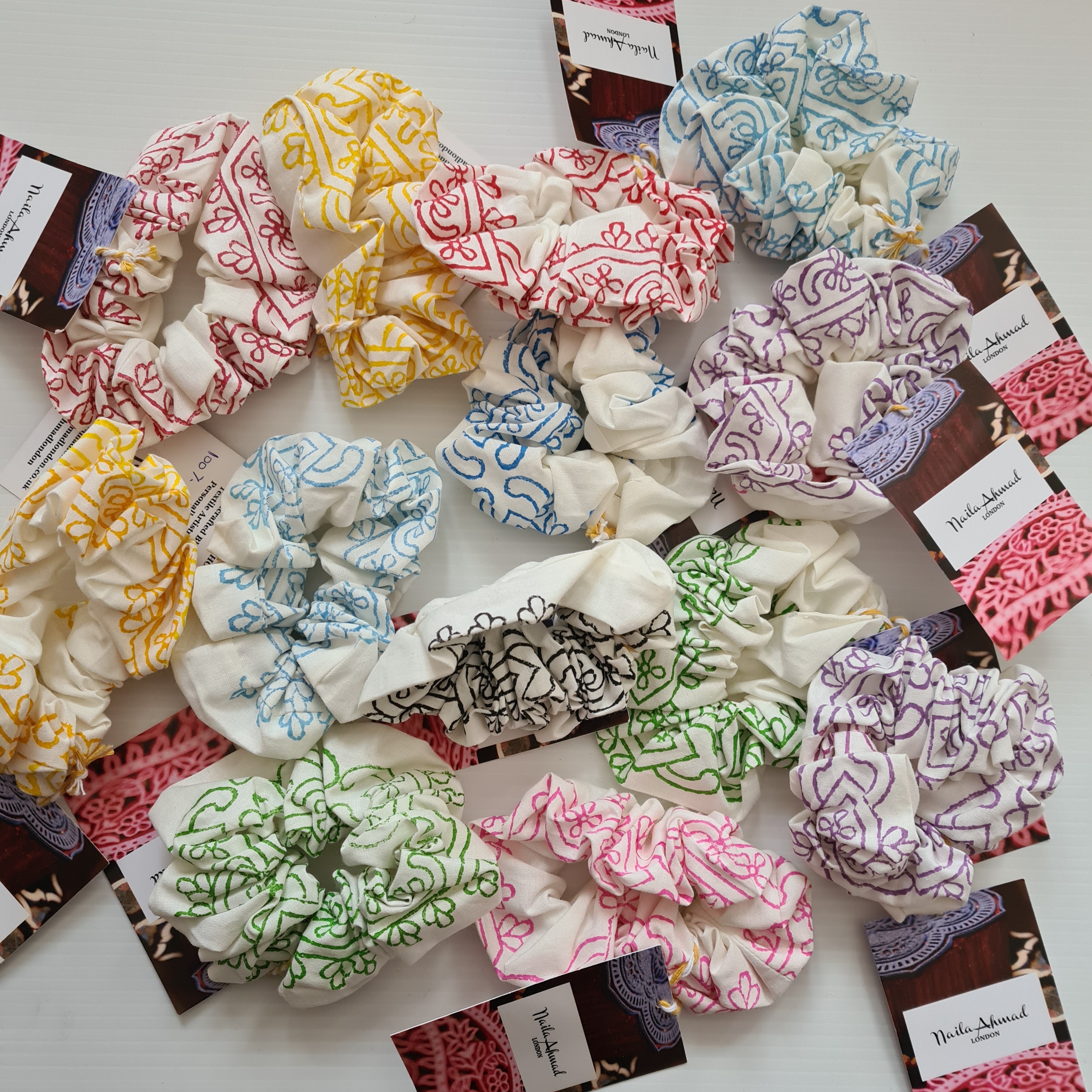 Collection of patterned scrunchies on a white background with visible brand labels.