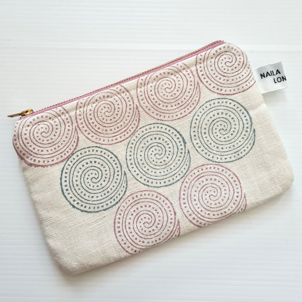 Fabric pouch with spiral pattern and visible brand tag on a white background
