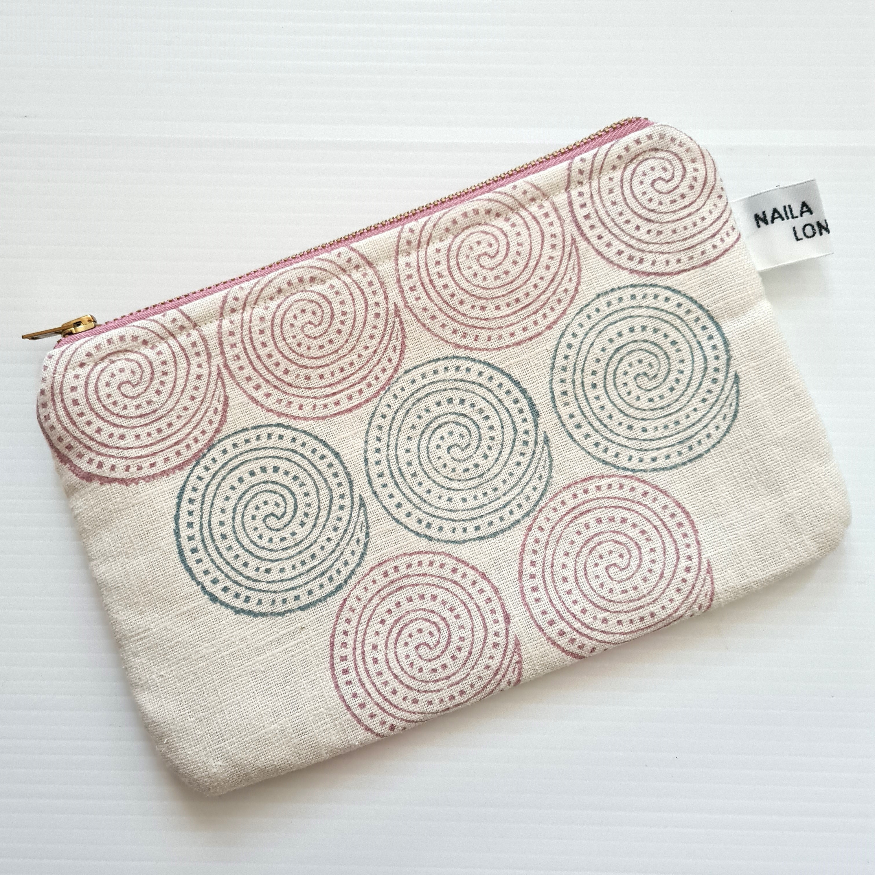 Fabric pouch with spiral pattern and visible brand tag on a white background