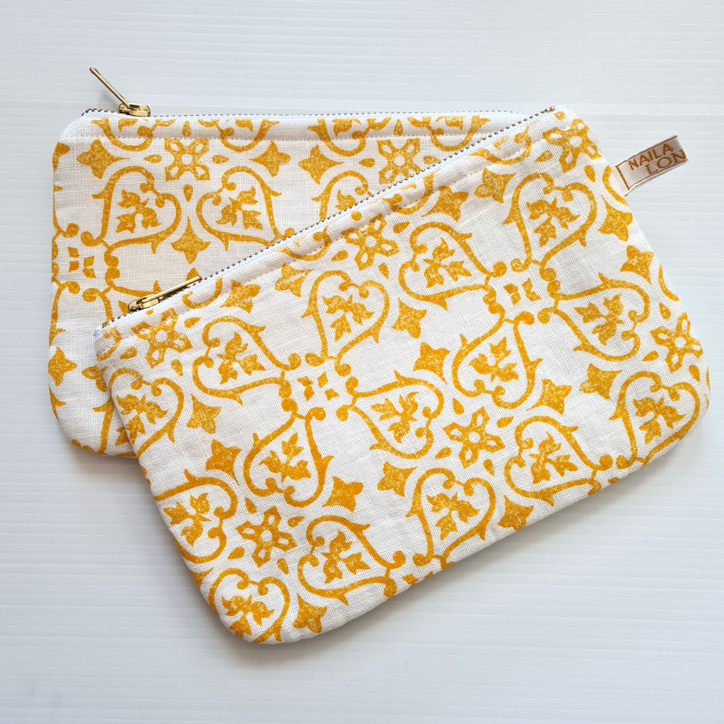 Two yellow patterned pouches on a white background
