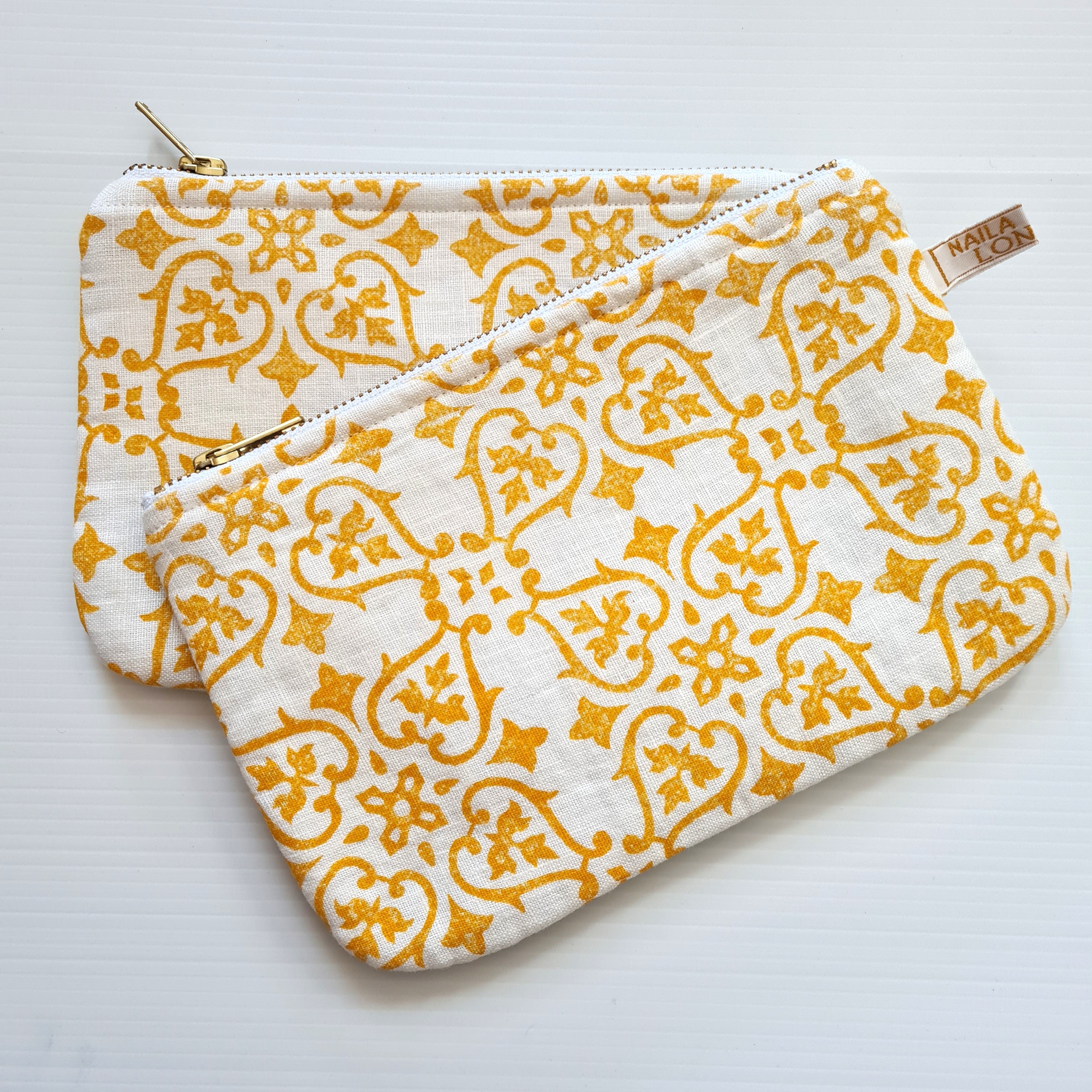 Two yellow patterned pouches on a white background