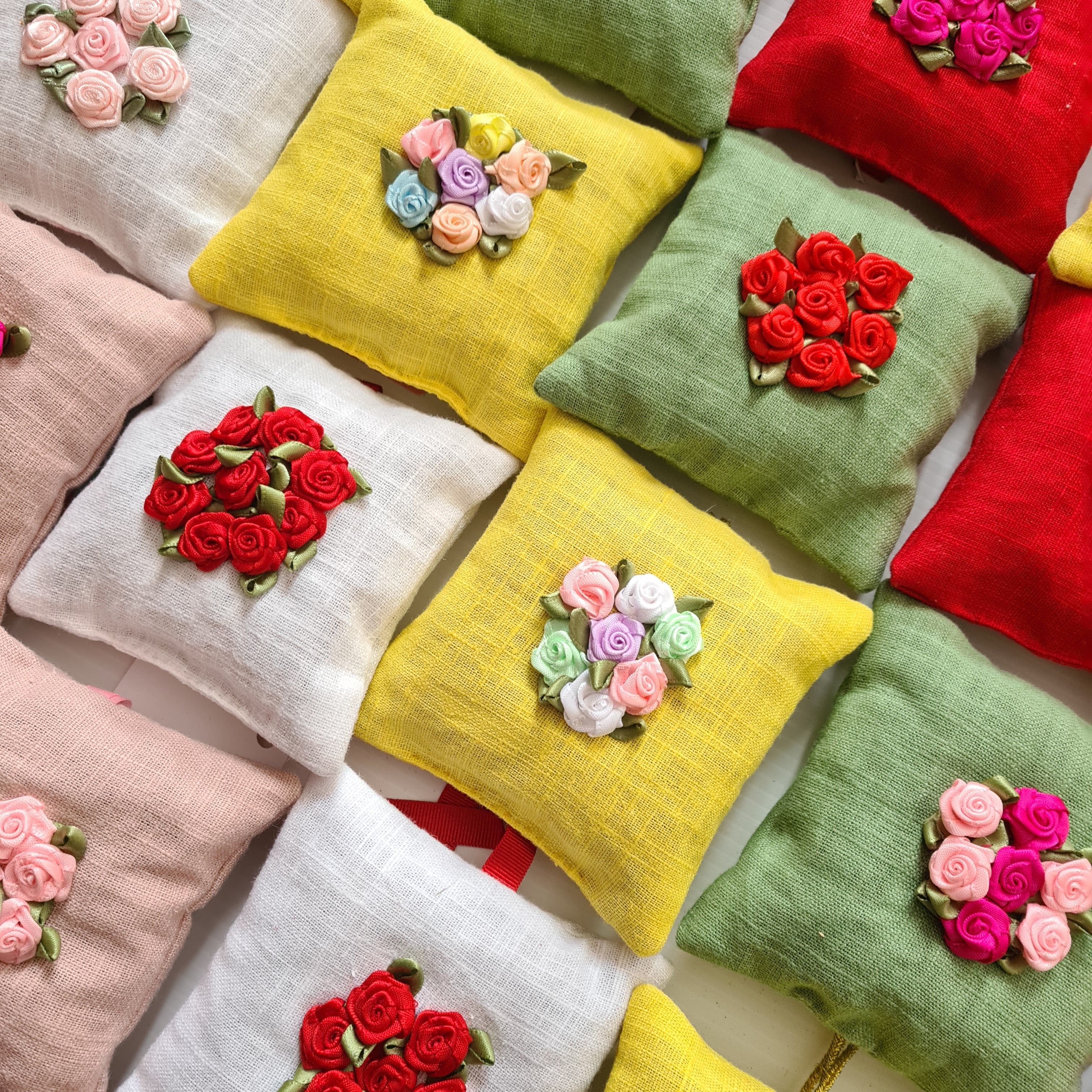Colorful pillows with embroidered floral designs on a white background