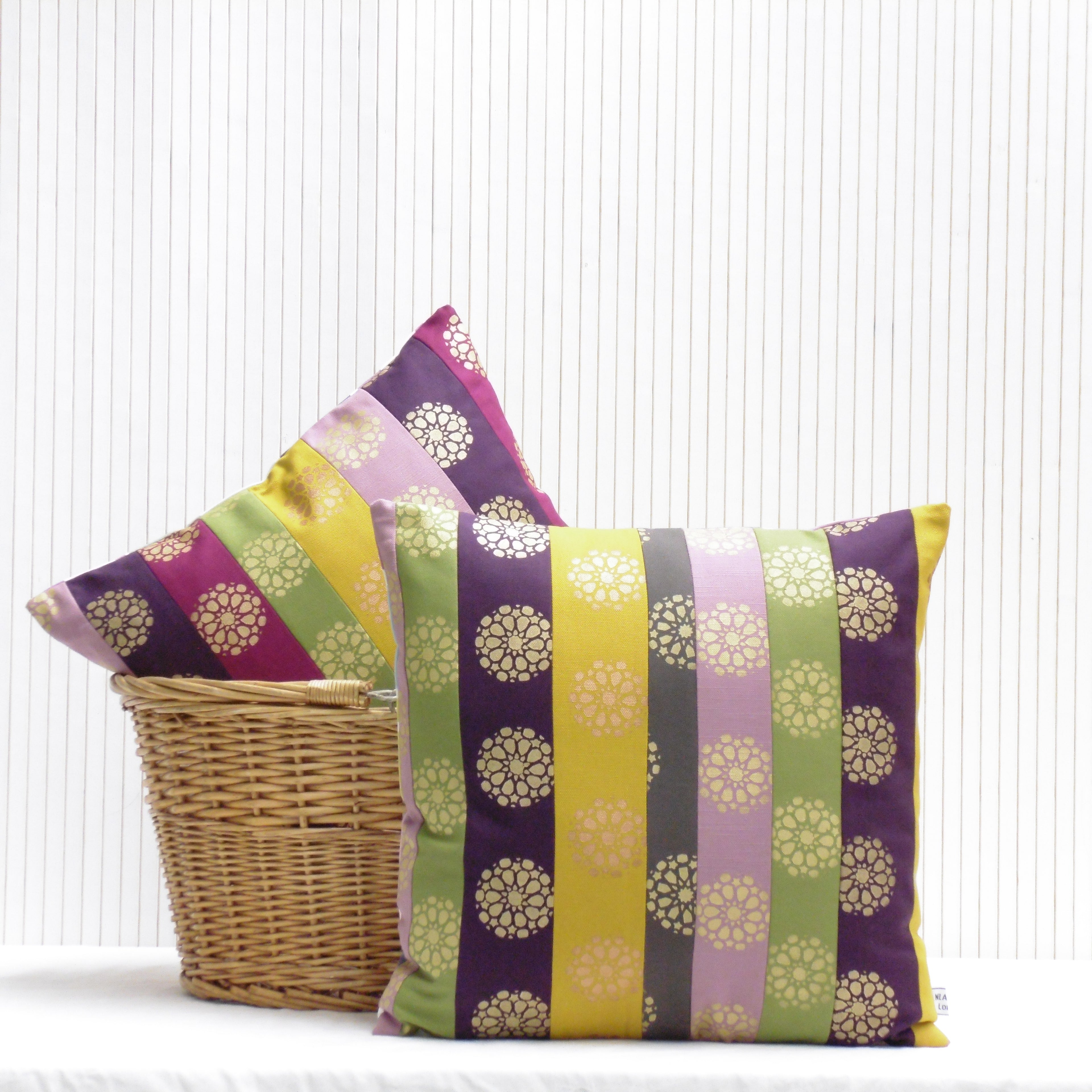 Colorful striped pillows with floral patterns in a wicker basket on a white background