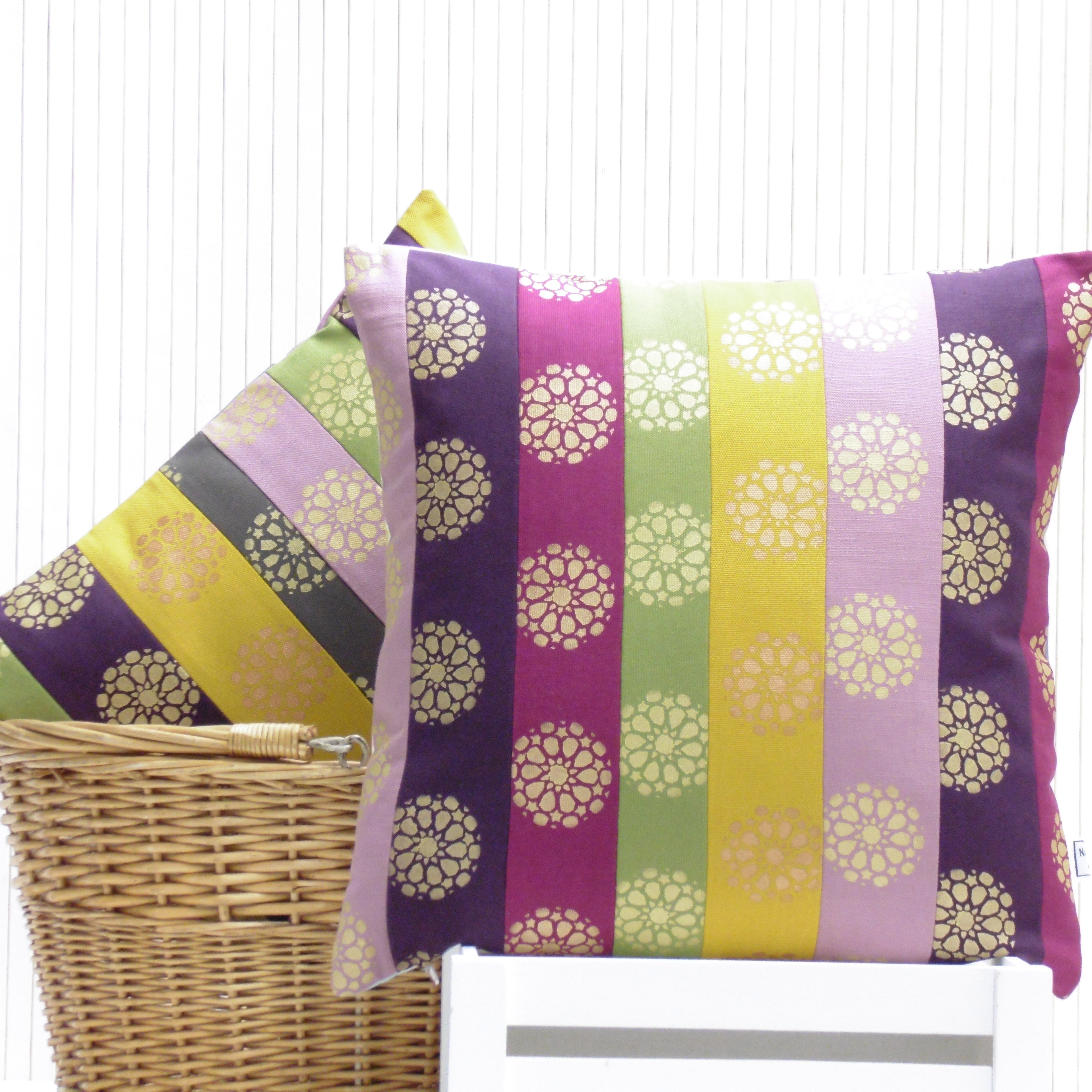 Decorative pillow with purple and yellow stripes and floral patterns on a white surface.