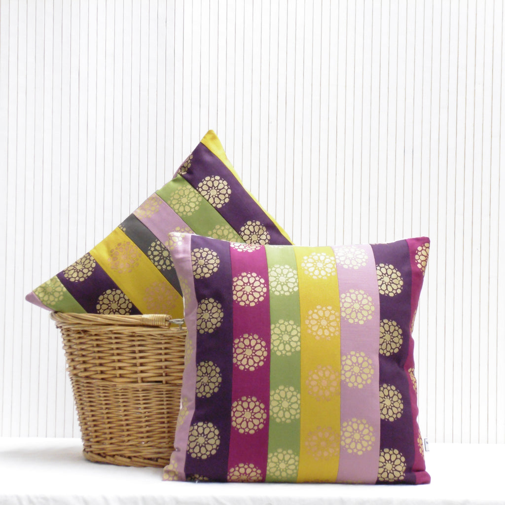 Two decorative pillows with purple and green stripes and floral patterns on a white background.