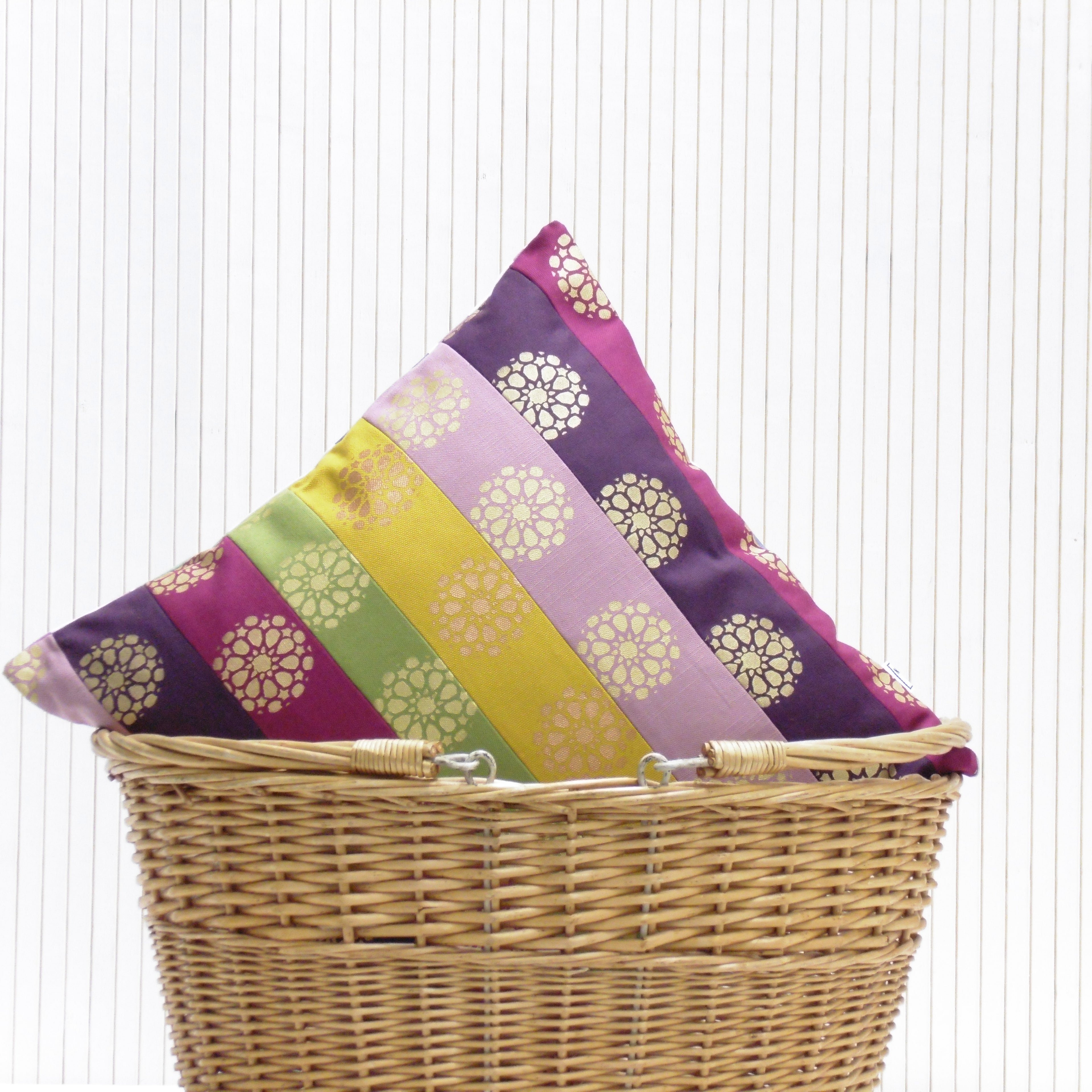 Colorful striped pillow with floral patterns in a wicker basket on a white background