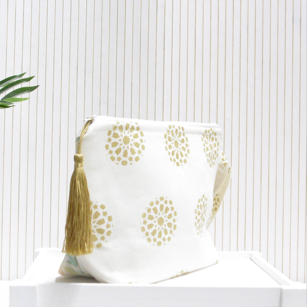 White pouch with gold patterns and tassels on a white background