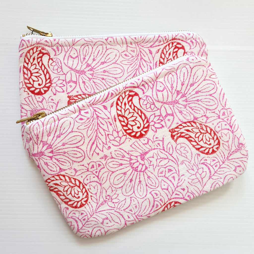 Pink and white patterned pouches with gold zippers on a white background