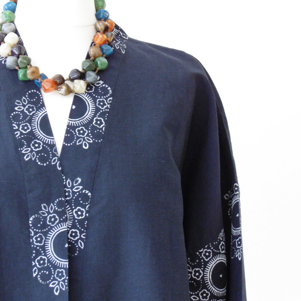 Navy blue garment with white patterns and a colorful necklace on a white background