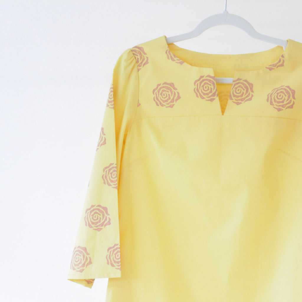 Yellow top with pink rose patterns on a white background